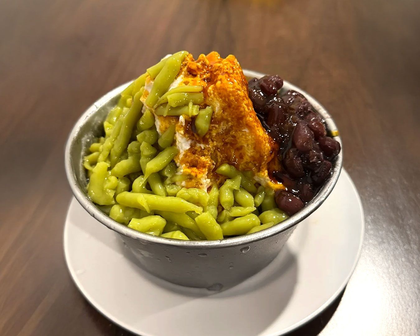 A traditional Malaysian dessert with green pandan jelly, creamy coconut milk, and dark palm sugar syrup.