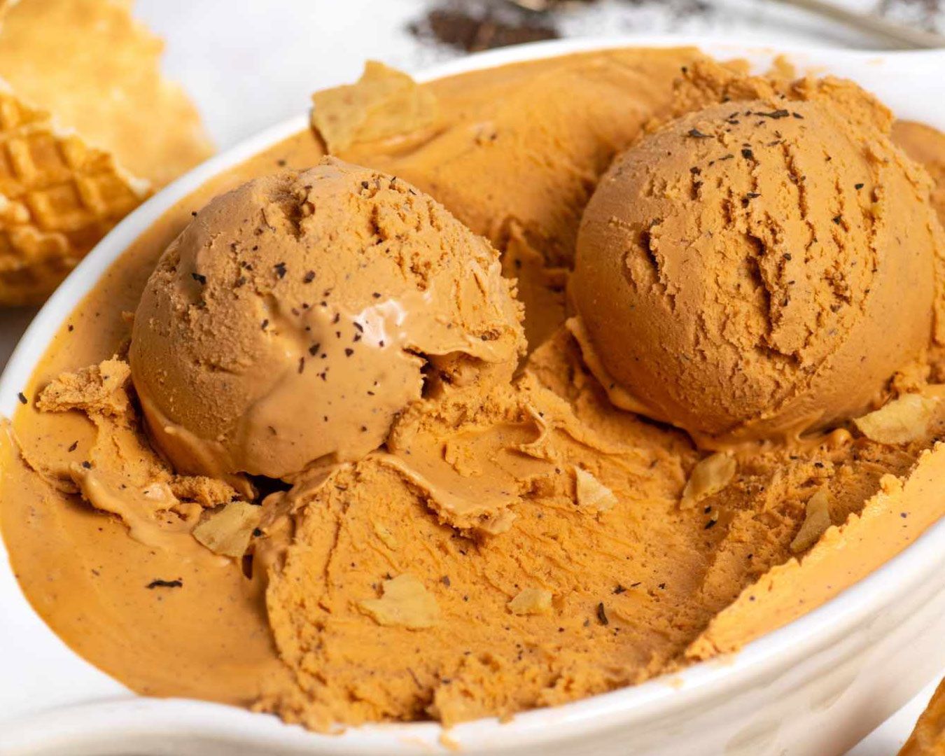 A creamy scoop of Thai milk tea gelato in a serving cup, featuring a rich caramel-brown colour that reflects its tea-infused flavour.