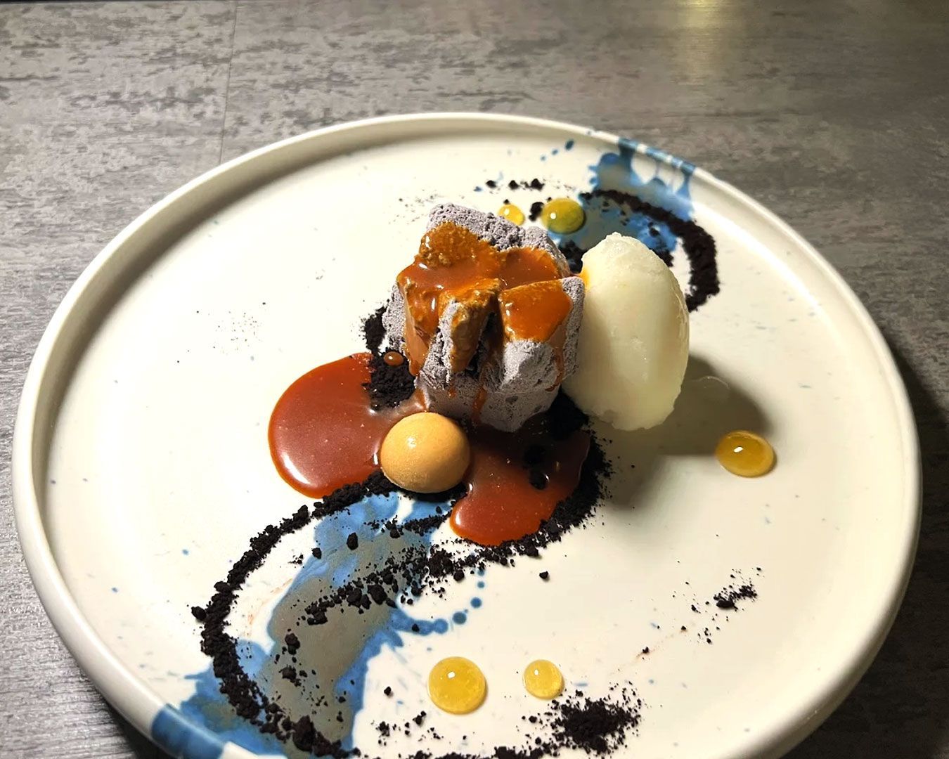 A plated dessert combining glossy dark chocolate with silky durian mousse, presented with modern fine-dining artistry.