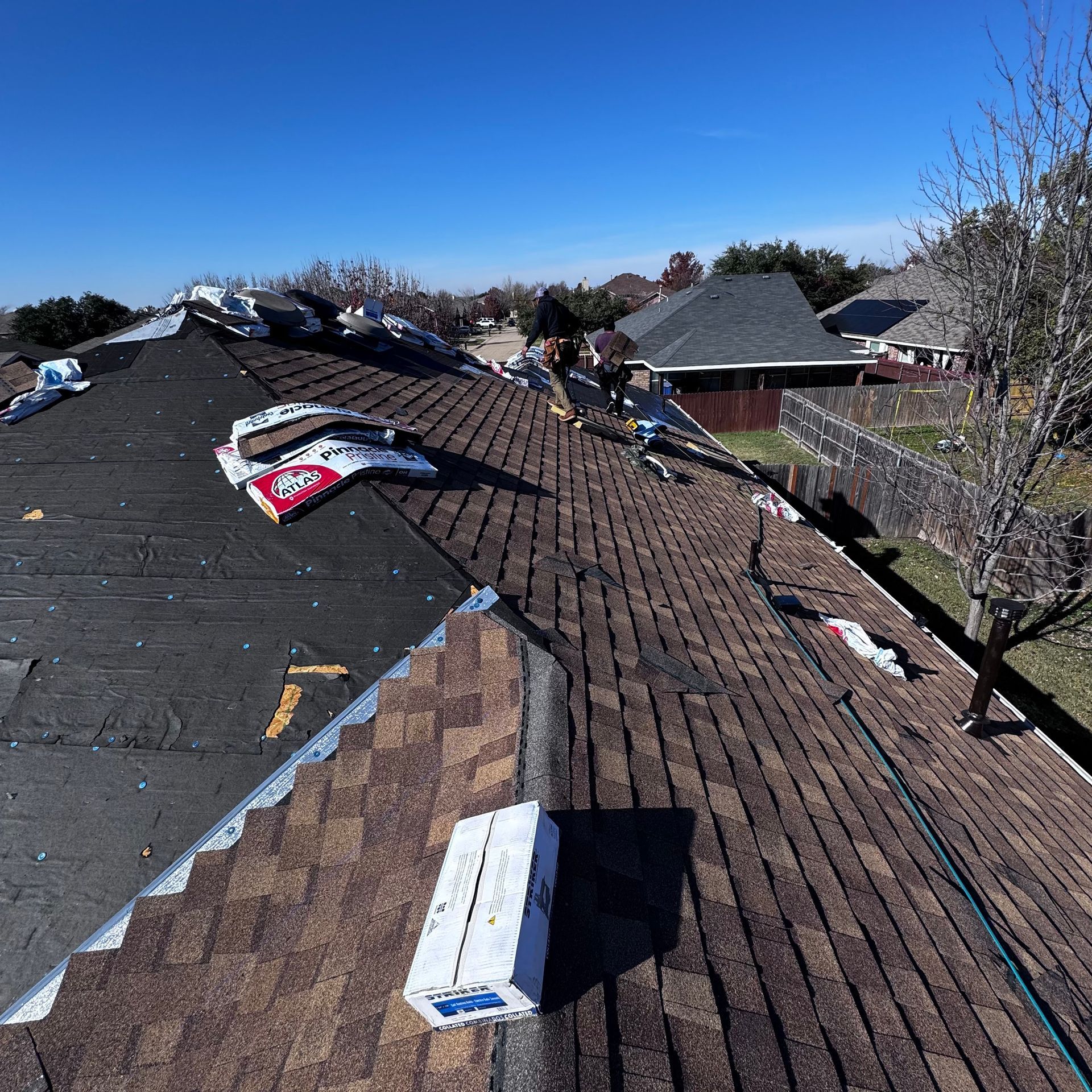Two-story house with a beige exterior, wooden accents, two-car garage, and a blue sky.