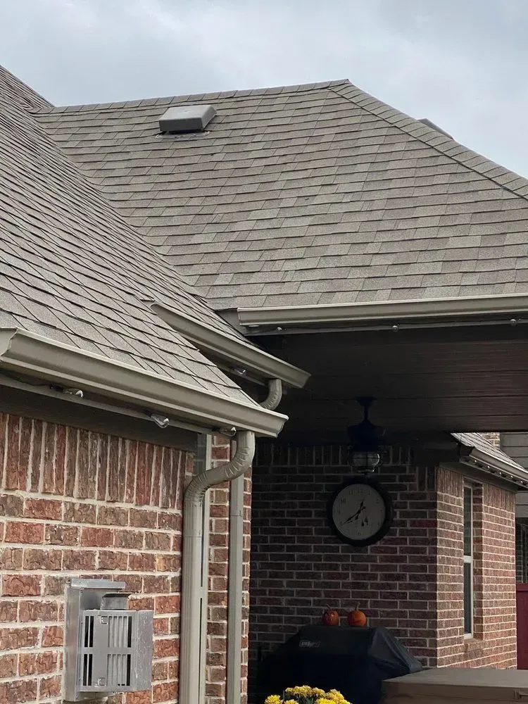 Brick home exterior with shingled roof, gutters, and clock.