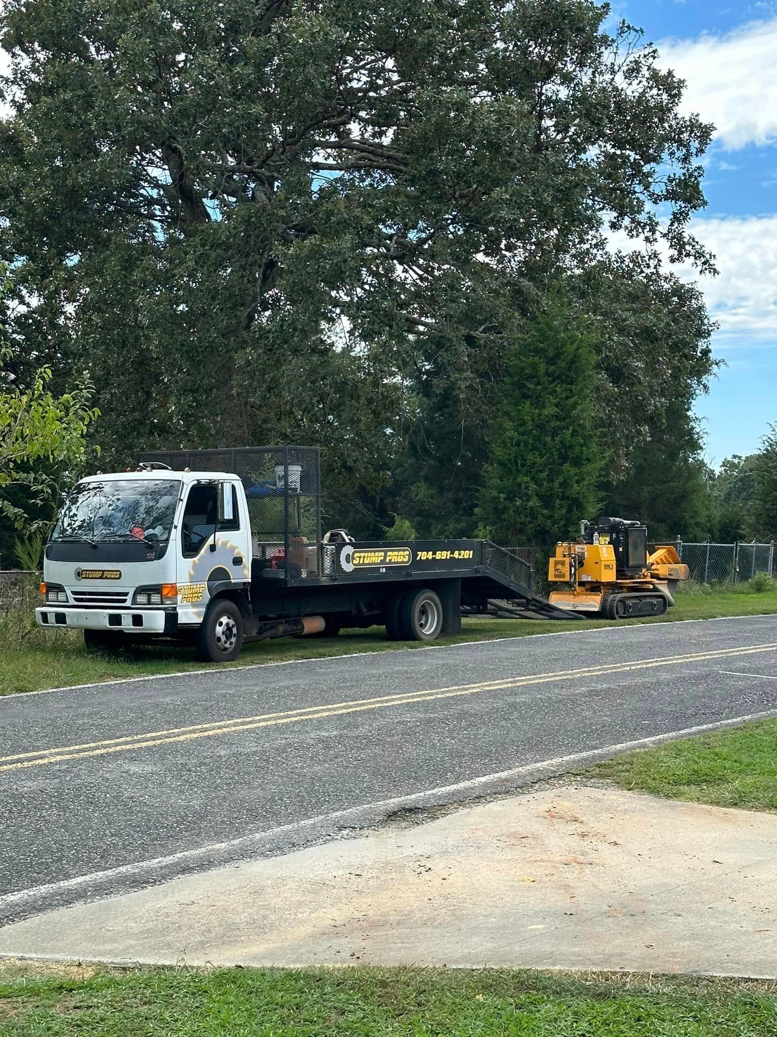 A tow truck is parked on the side of the road next to a bulldozer.