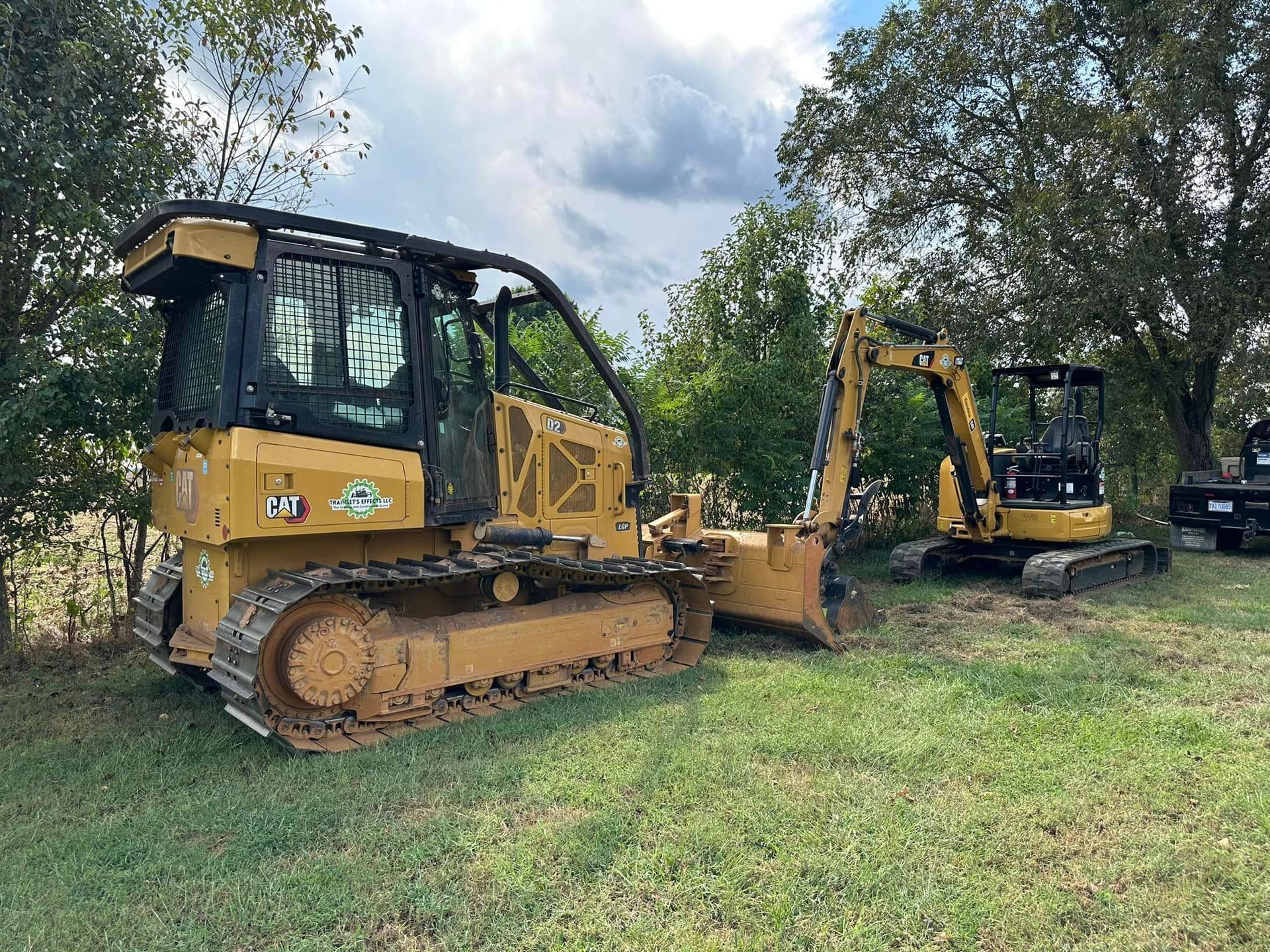 A bulldozer and an excavator are parked in a grassy field.