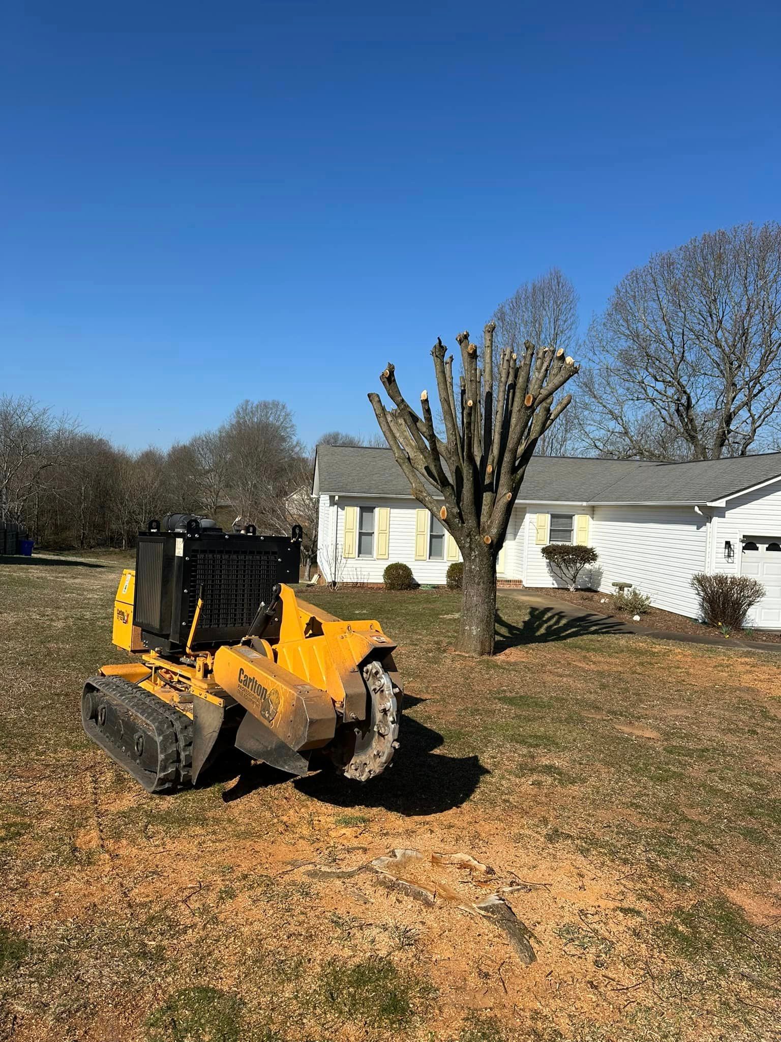 A yellow tractor is sitting in a grassy field in front of a house.