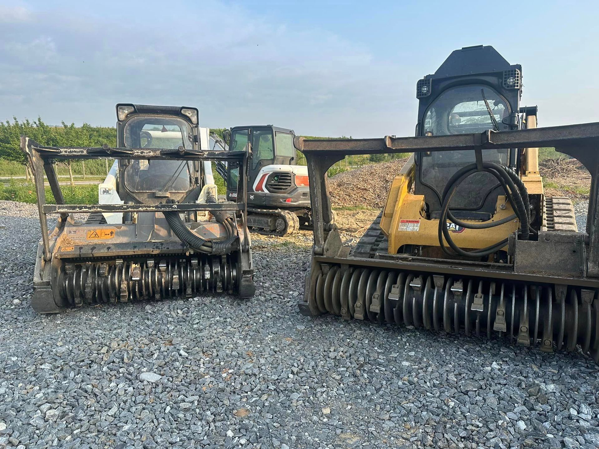 Two tractors are parked next to each other on a gravel road.