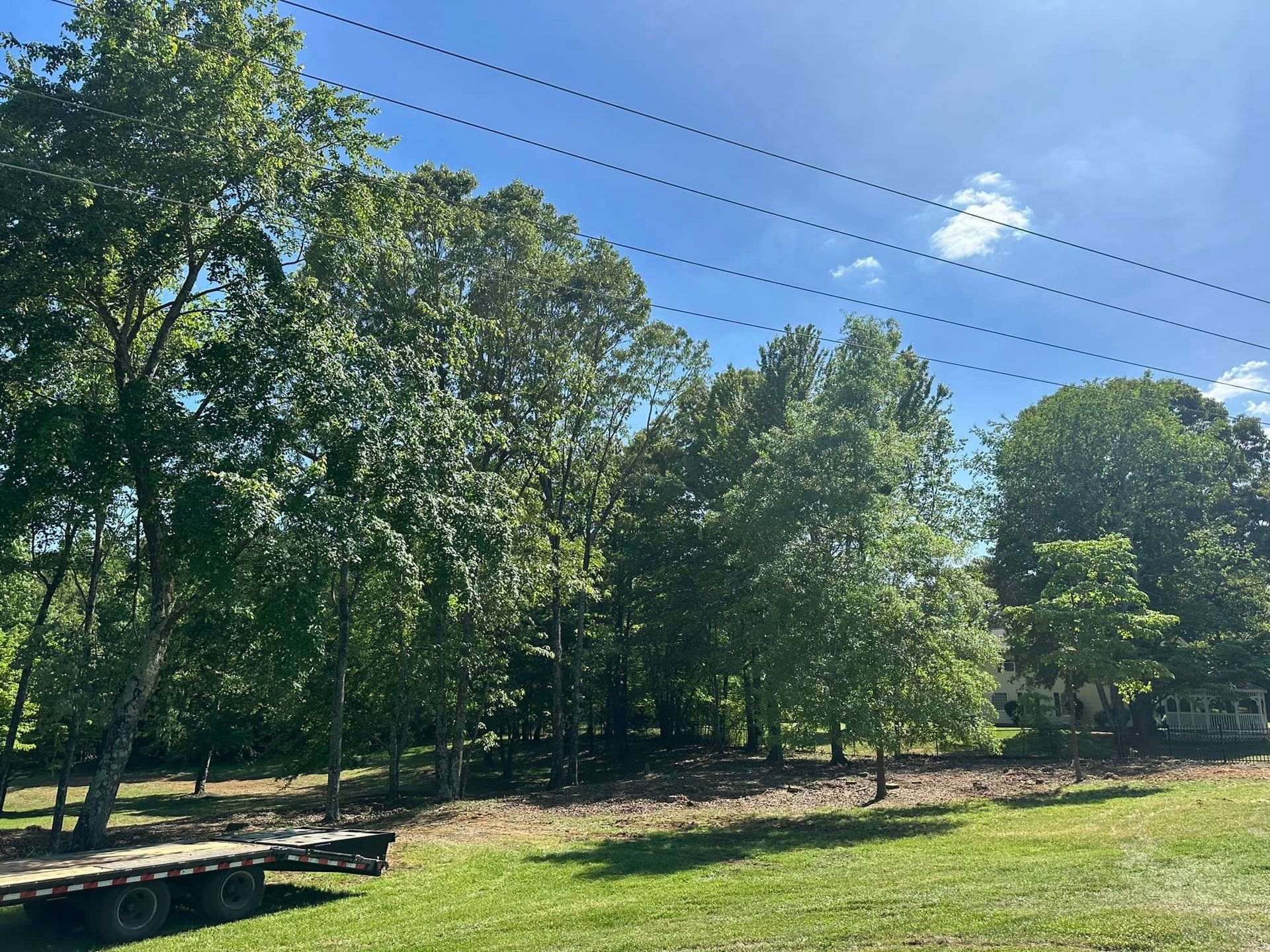 A trailer is parked in a grassy field with trees in the background.