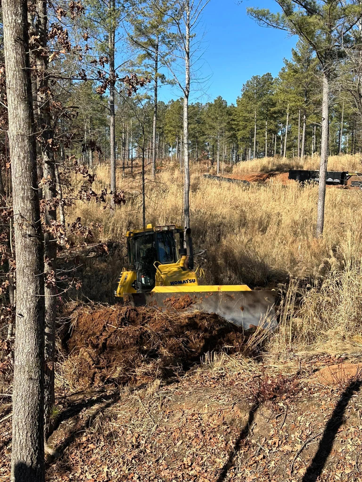 A bulldozer is plowing a field in the woods.