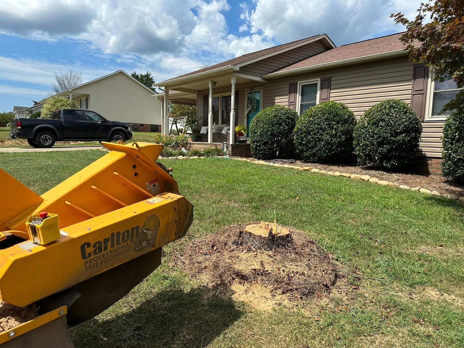 A stump grinder is sitting in front of a house.