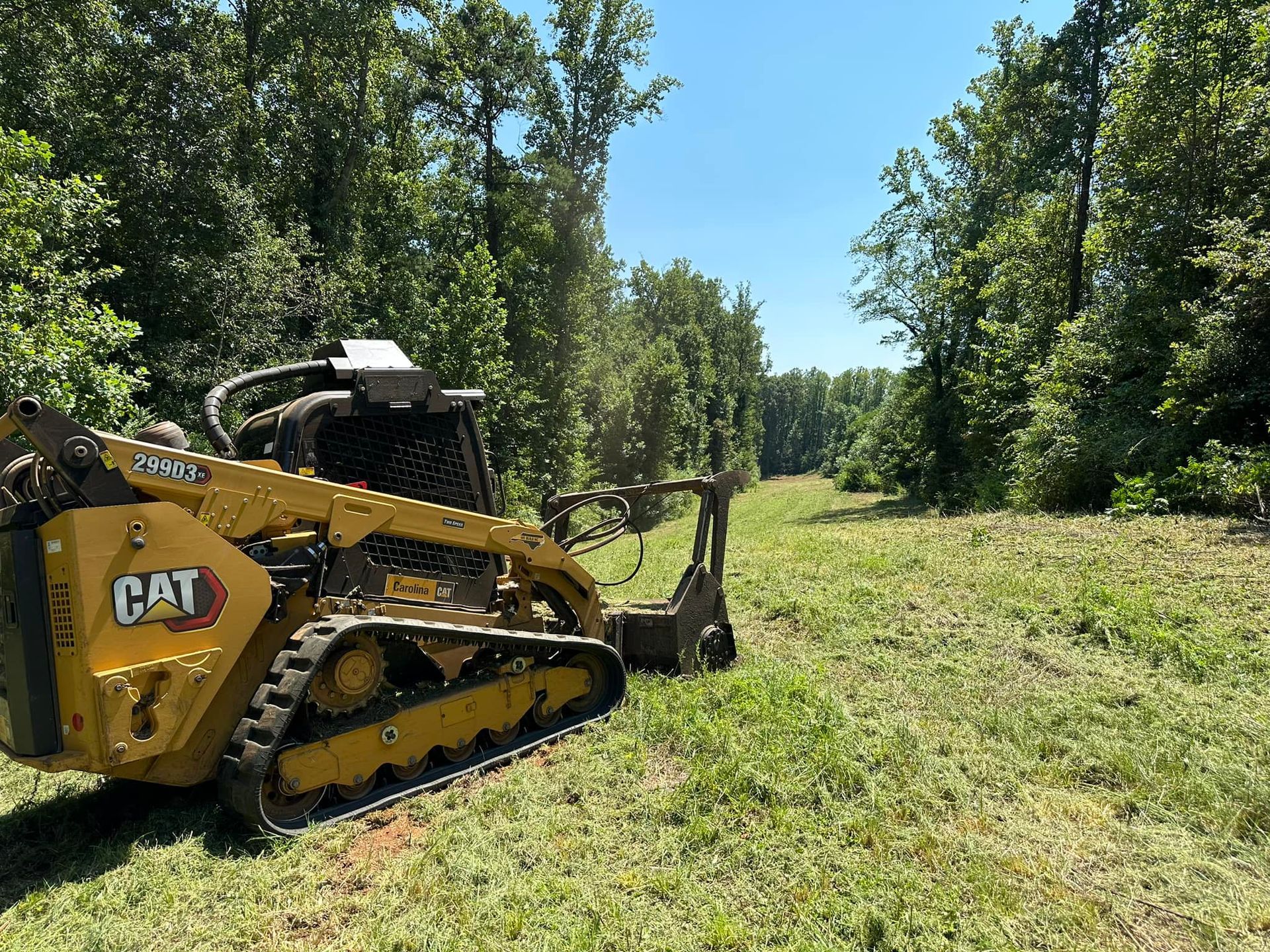 A yellow cat tractor is sitting in a grassy field.