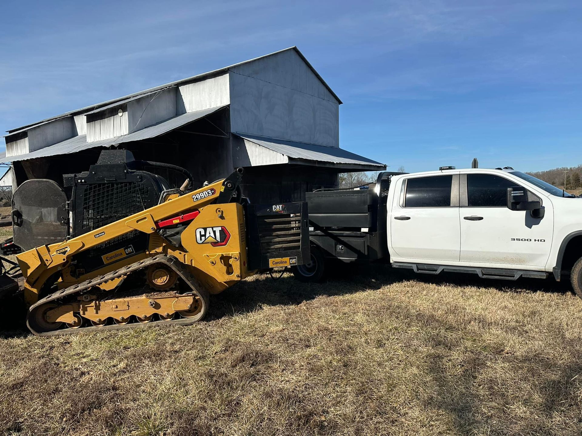 A bulldozer is being towed by a white truck in a field.