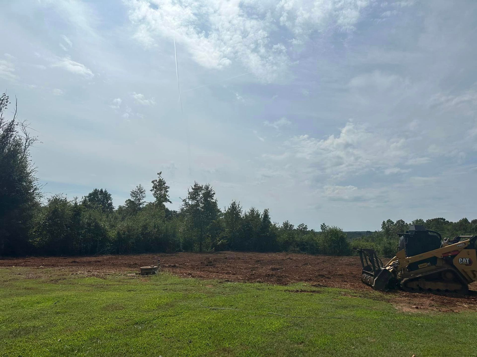 A bulldozer is sitting in the middle of a grassy field.