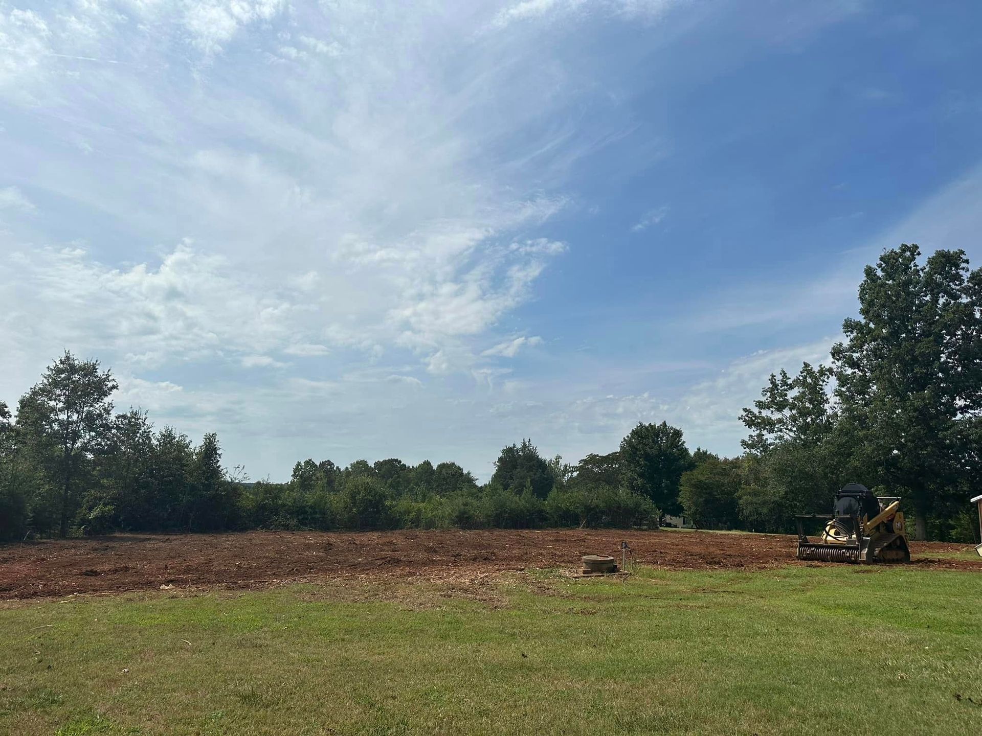 A bulldozer is sitting in the middle of a grassy field.