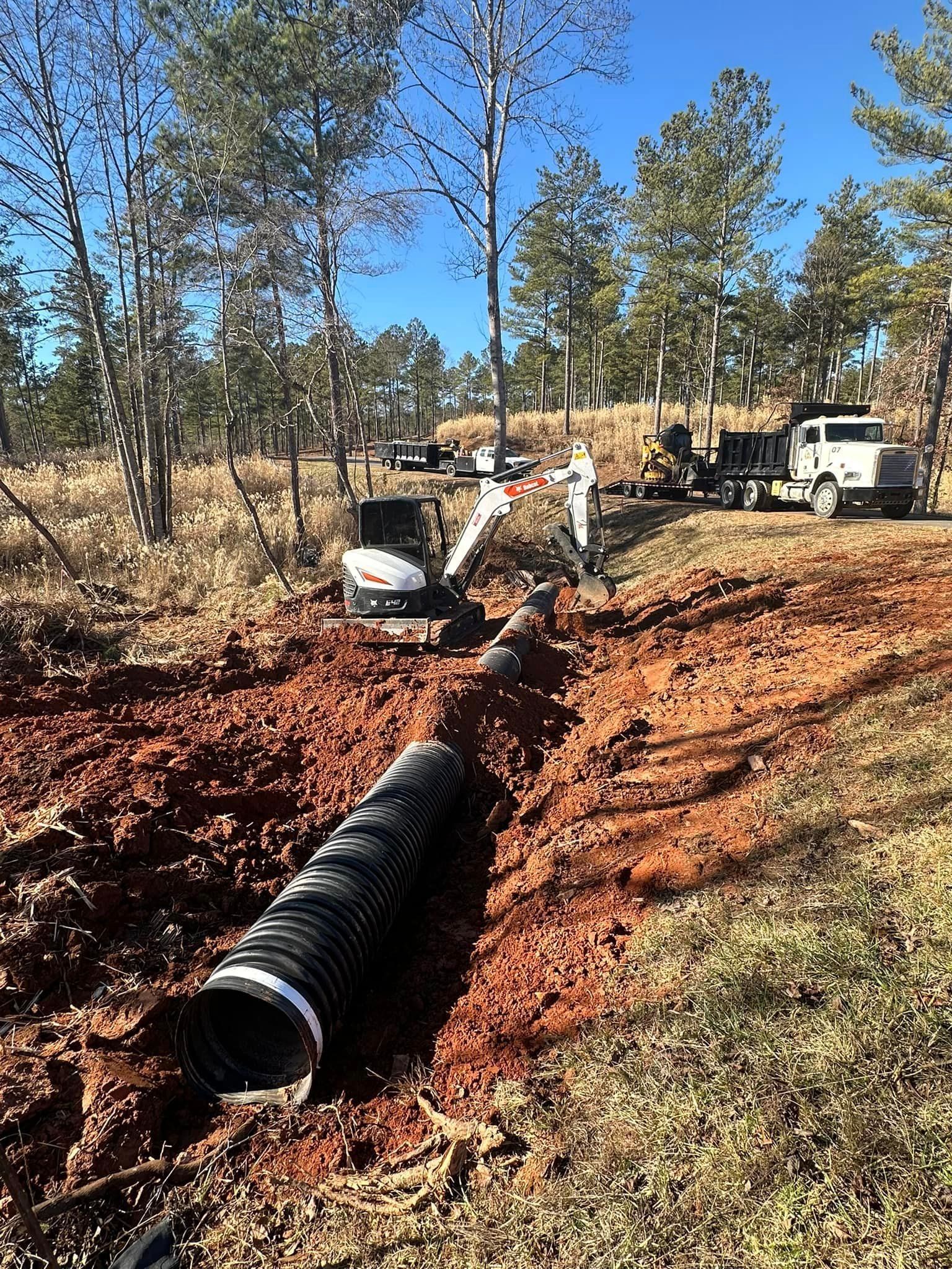 A large pipe is being installed in the dirt in a field.