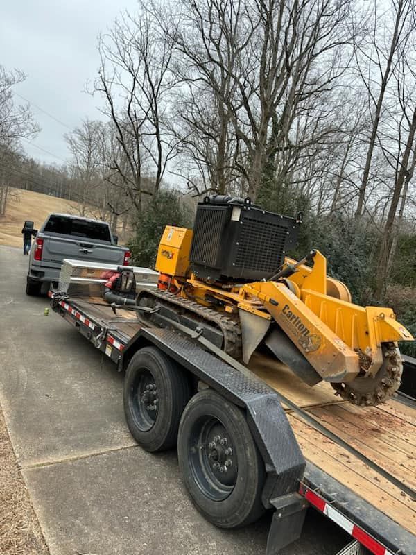 A truck is towing a stump grinder on a trailer.