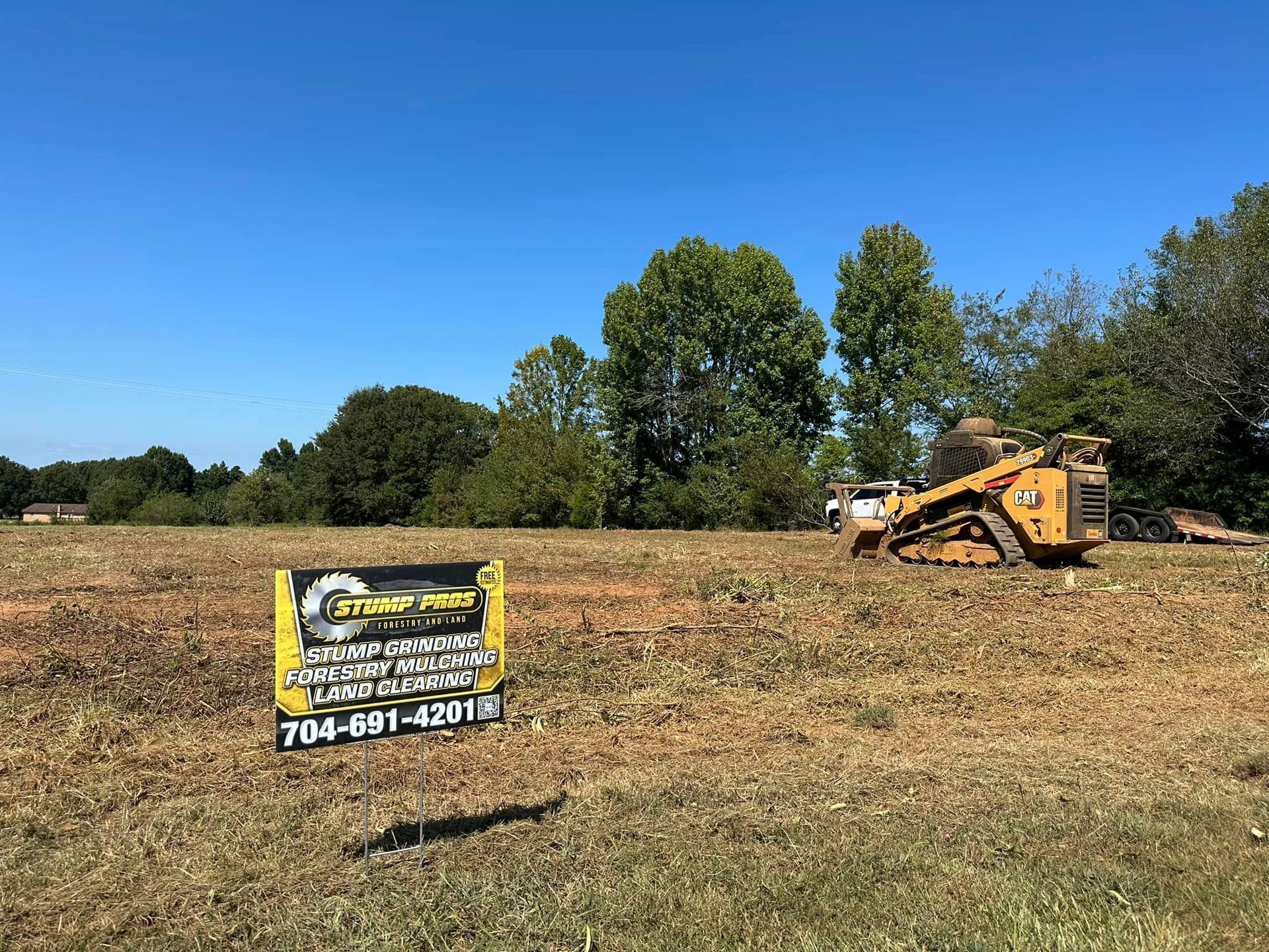 A bulldozer is sitting in the middle of a field next to a sign.