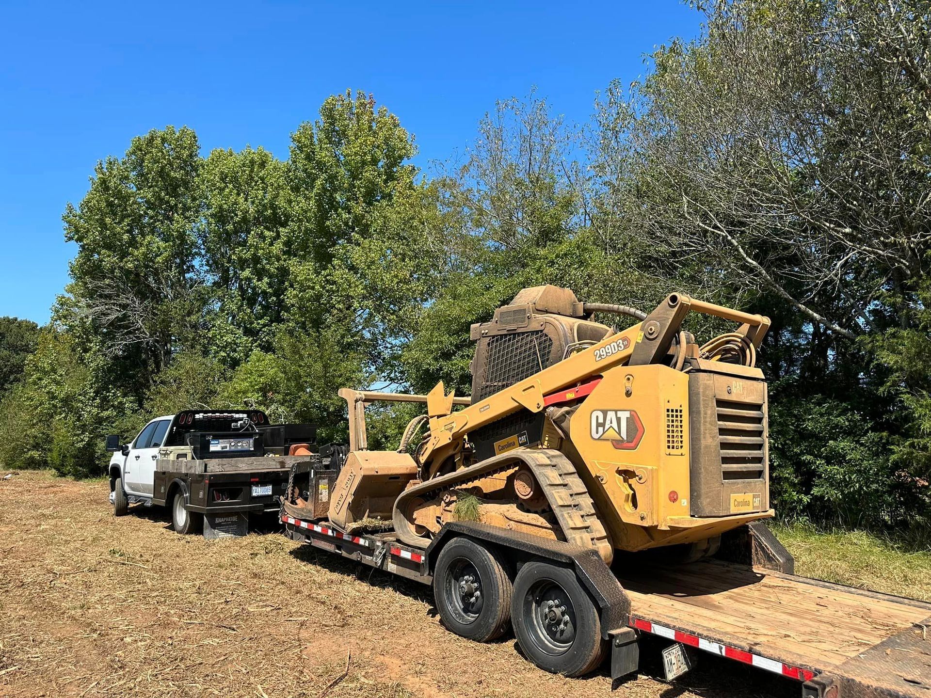 A cat bulldozer is being towed by a truck on a trailer.
