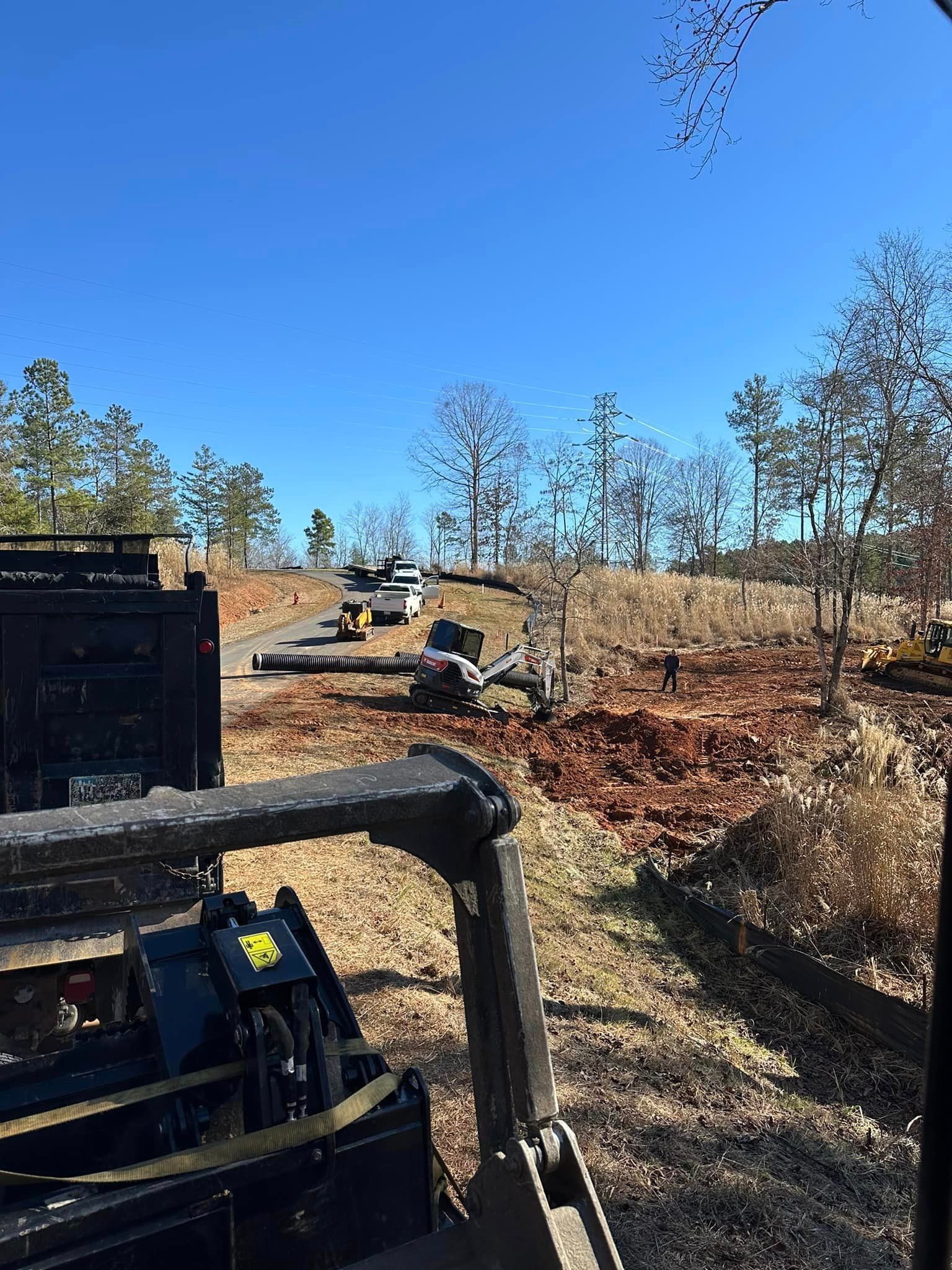 A forklift is driving through a field with trees in the background.