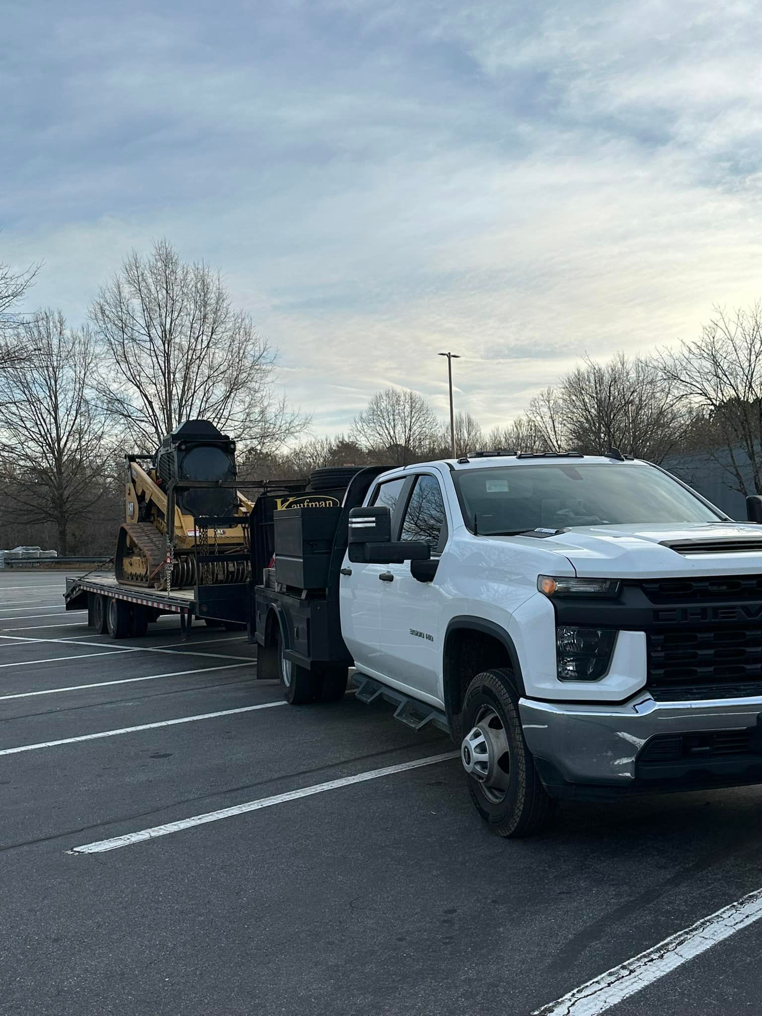 A white truck with a trailer attached to it is parked in a parking lot.