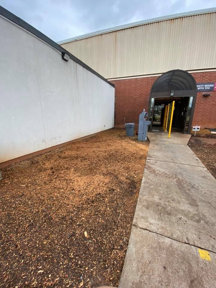 A brick building with a white wall and a walkway leading to it.