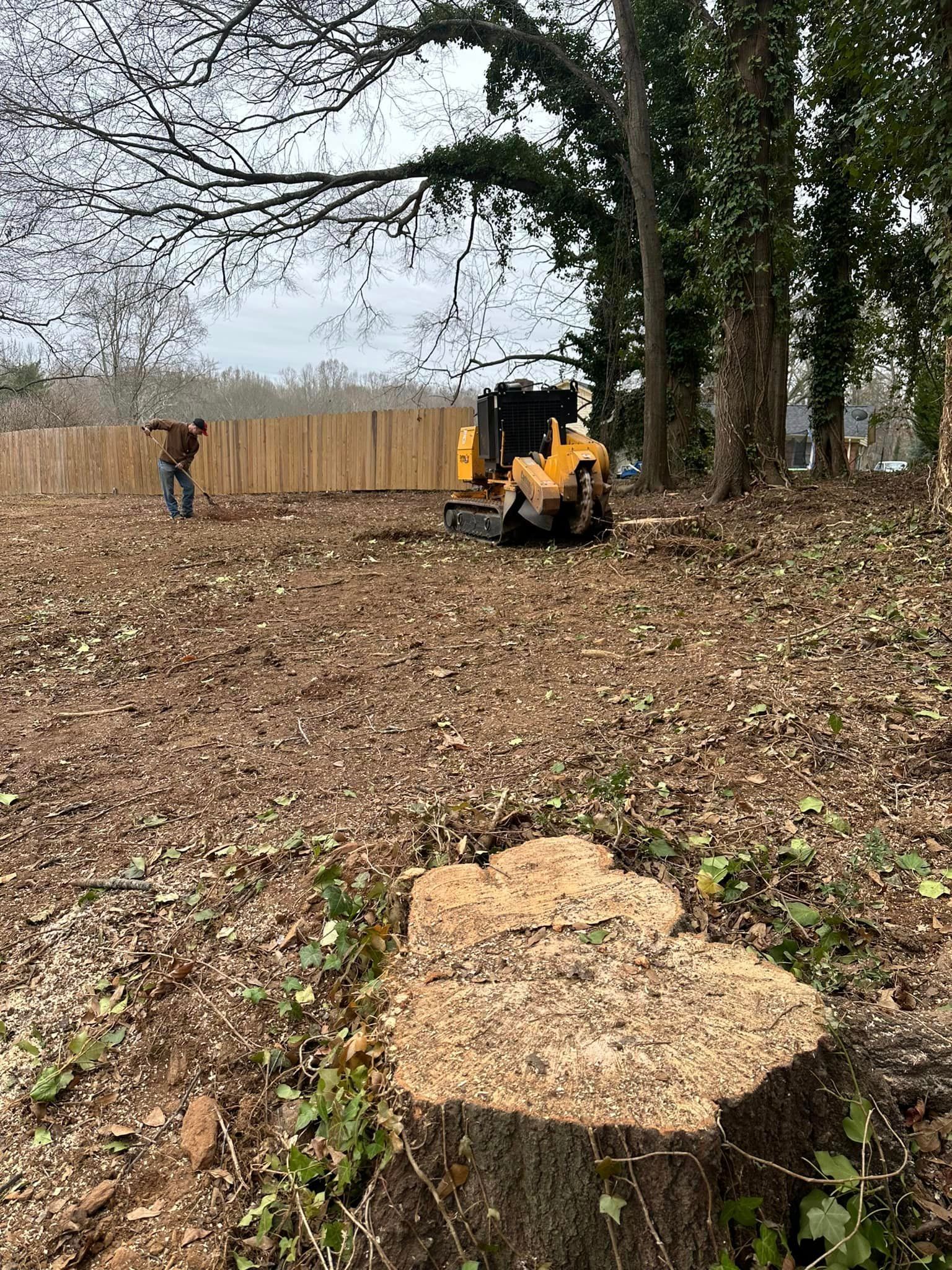 A tree stump is being removed by a machine in a field.