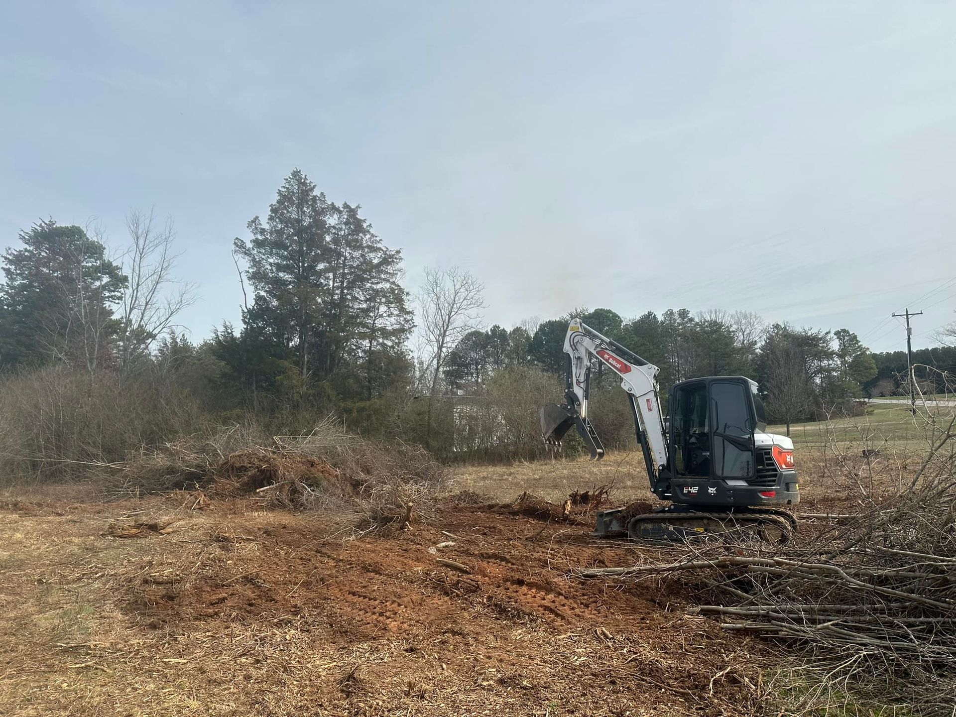 A small excavator is moving dirt in a field.