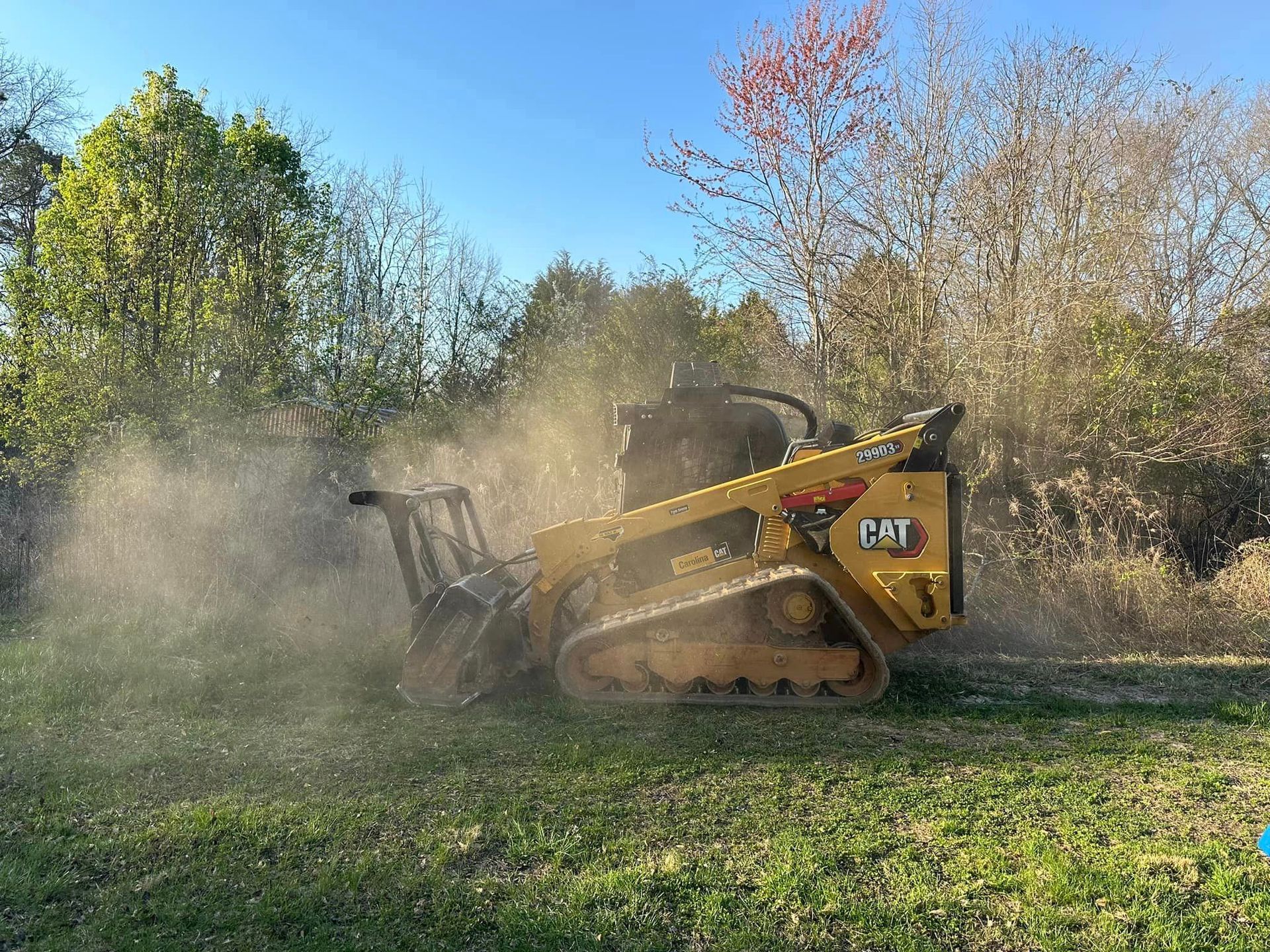A yellow cat tractor is cutting grass in a field.