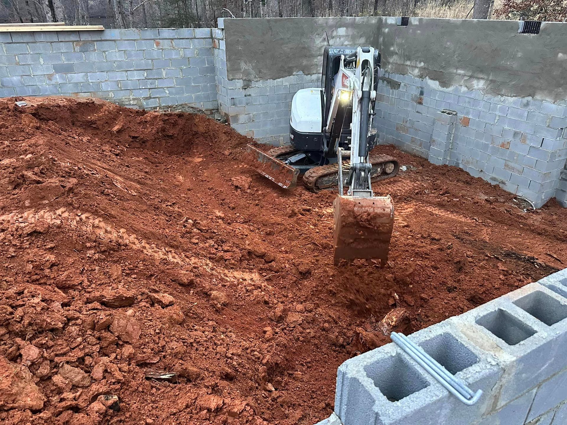 A small excavator is digging a hole in a pile of dirt.