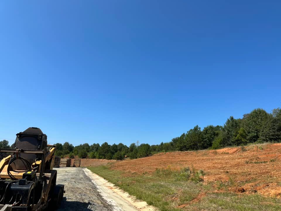 A bulldozer is parked on the side of a dirt road in a field.