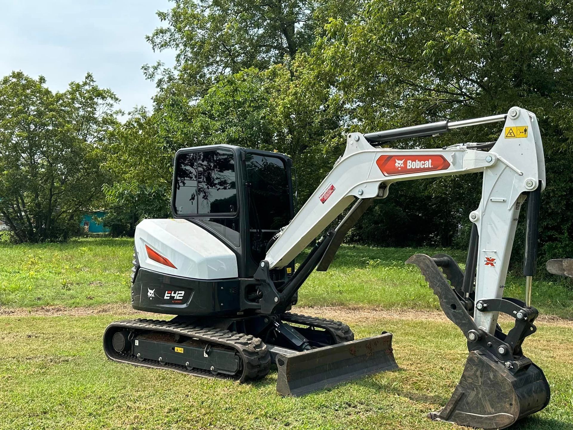 A small excavator is parked in a grassy field.