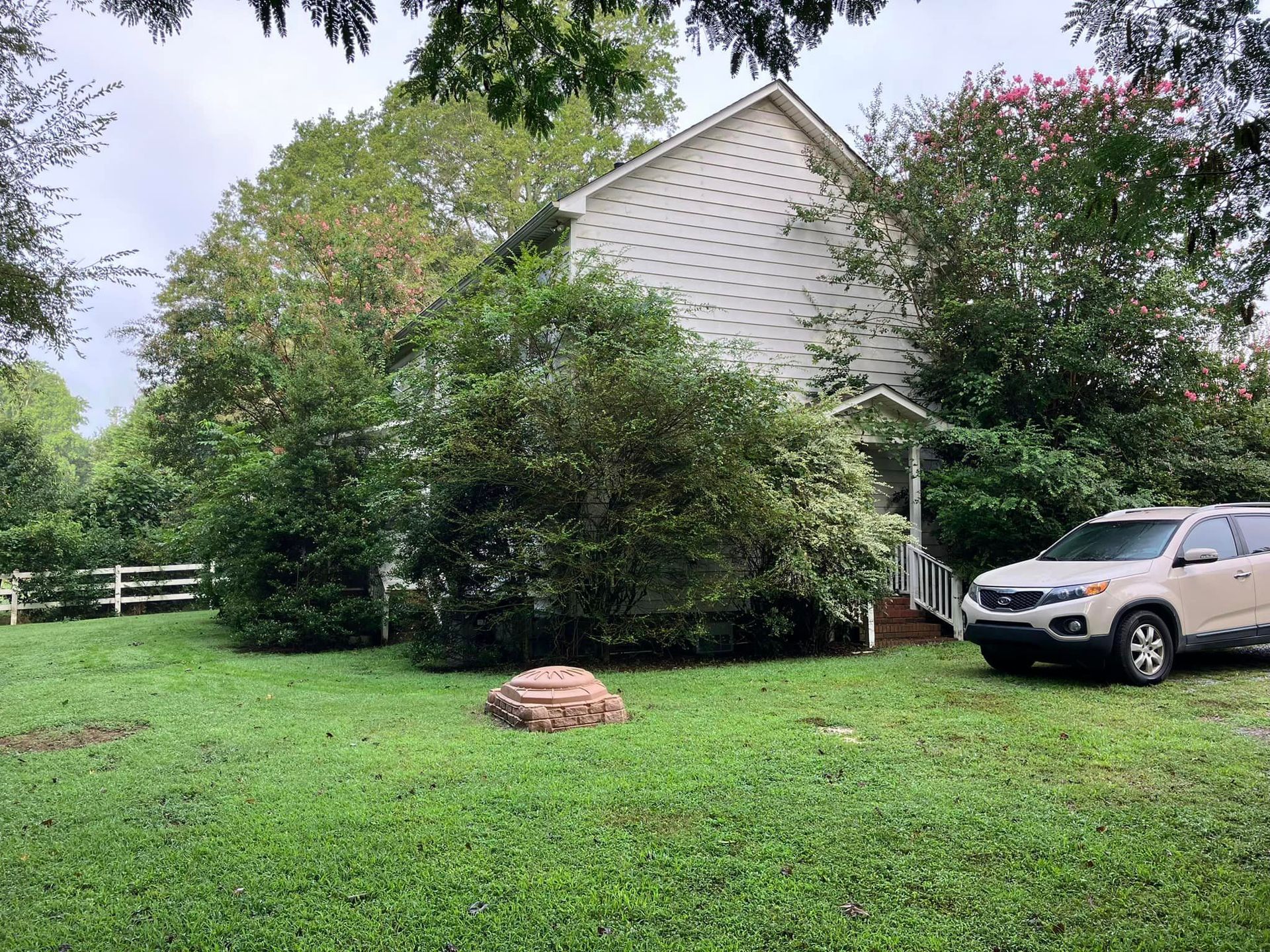 A white suv is parked in the grass in front of a house.