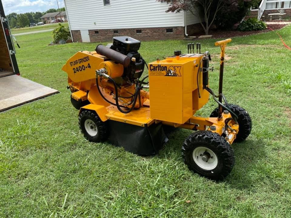 A yellow tractor is parked in the grass in front of a house.