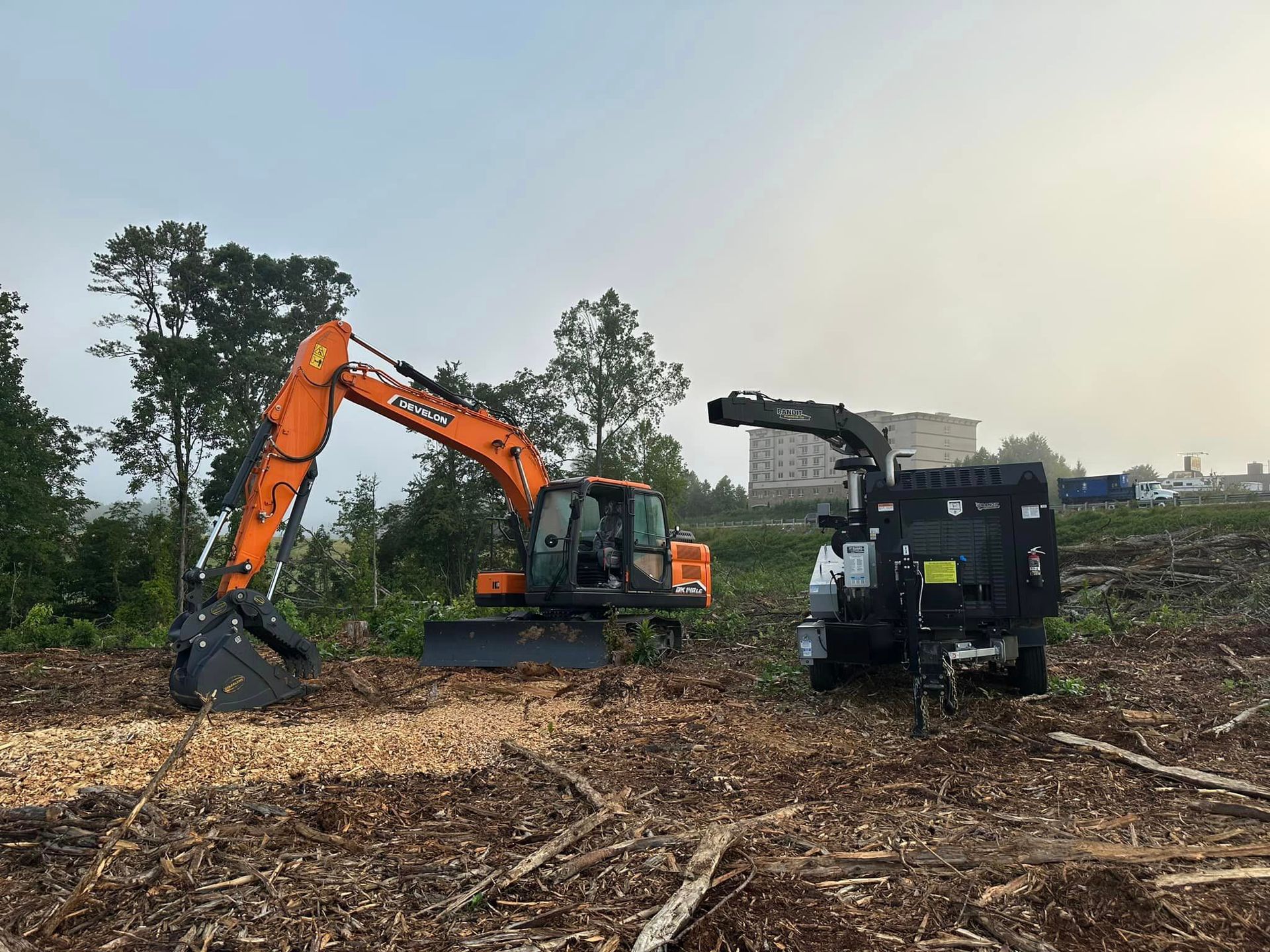 A large orange excavator is digging a hole in a field.