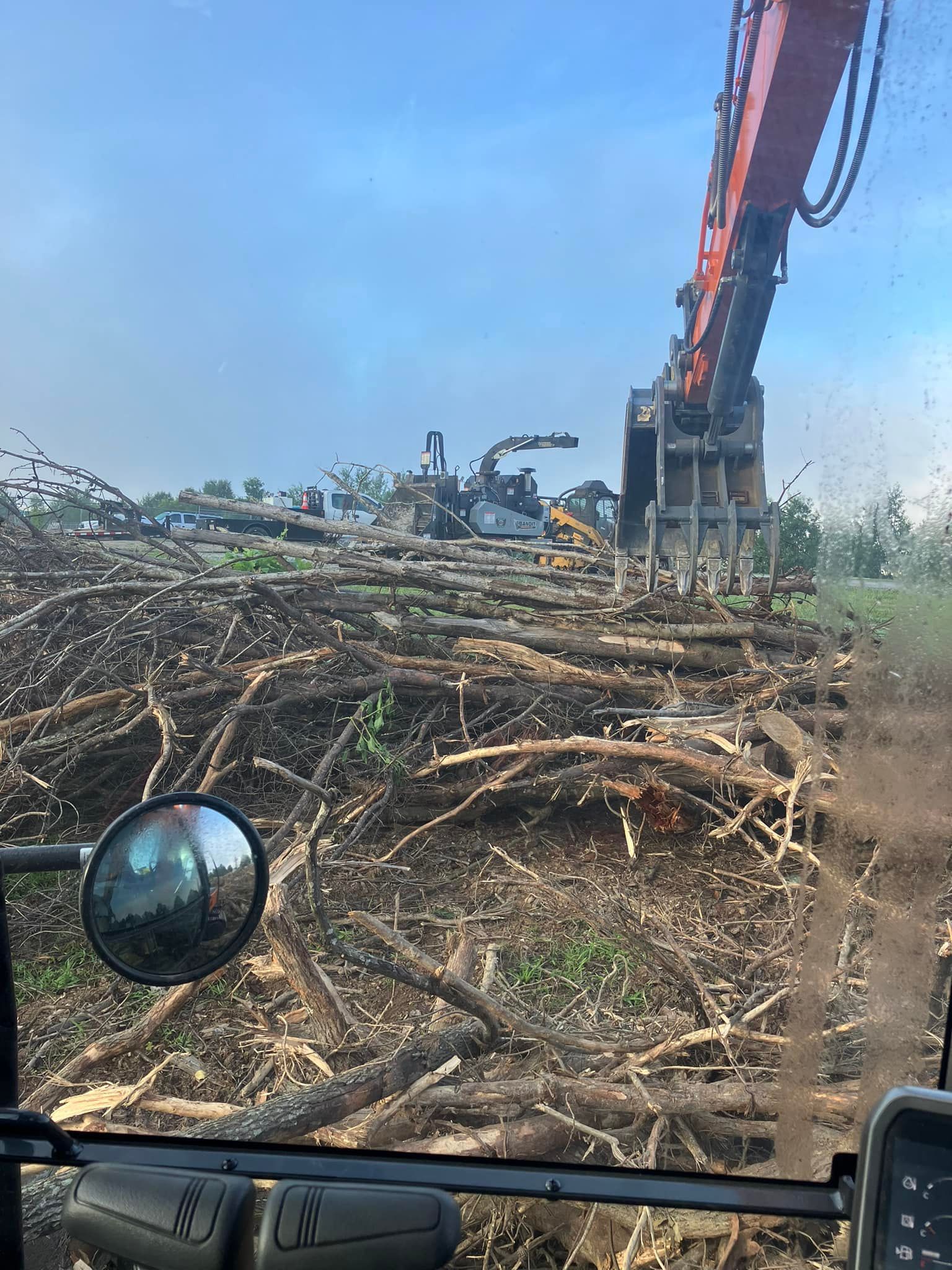 A truck is driving through a pile of logs in a field.