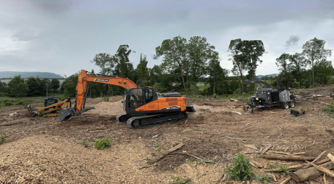 A large orange excavator is sitting in the middle of a dirt field.