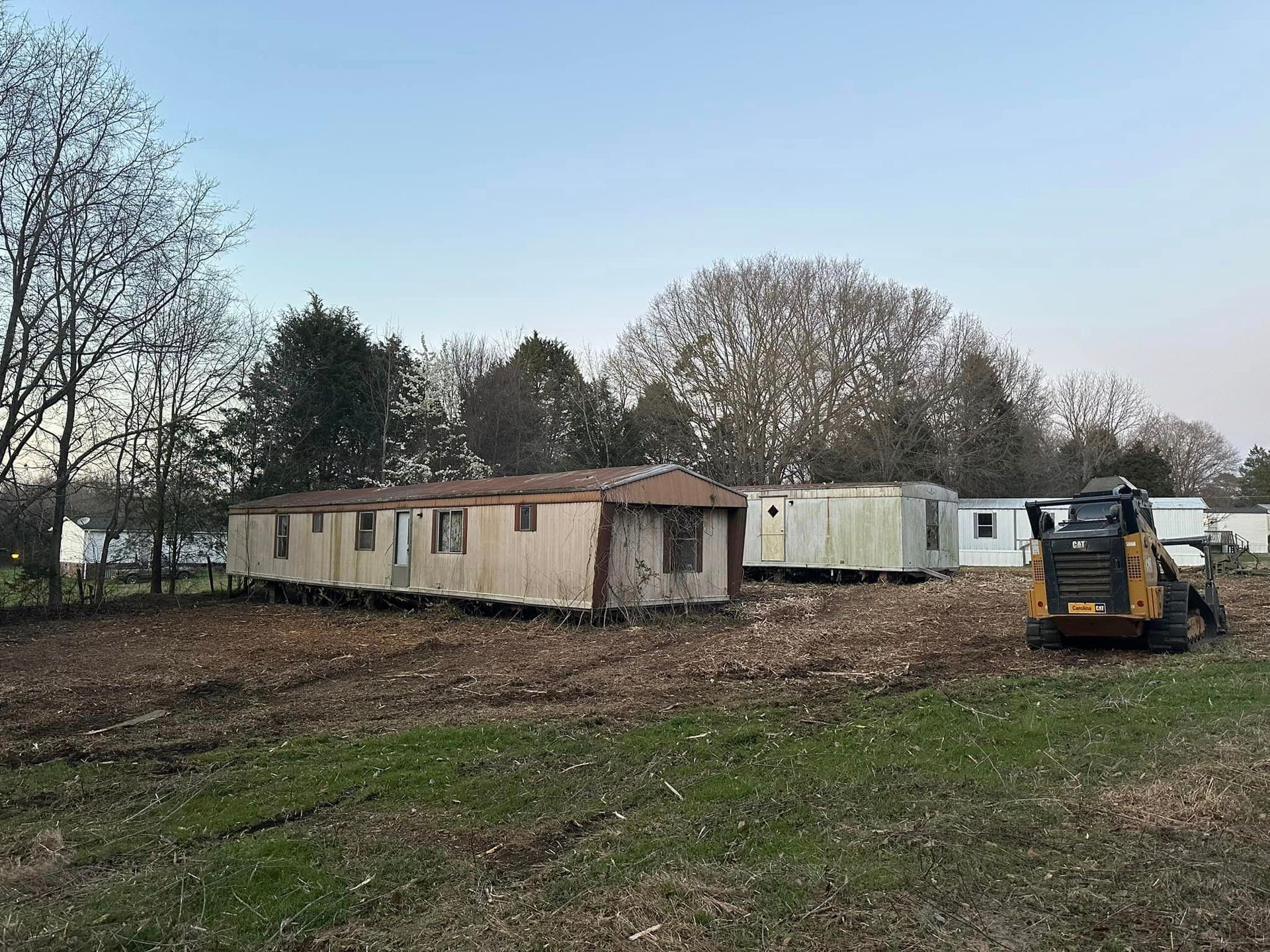 A group of mobile homes are sitting in a field next to a bulldozer.