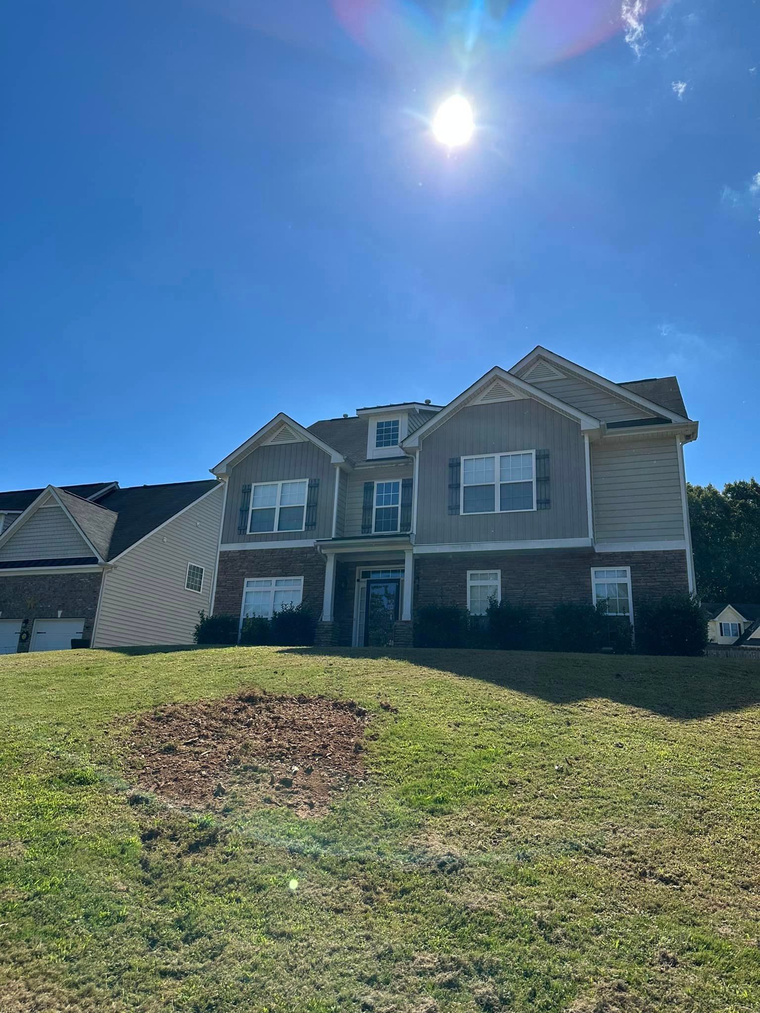 A large house is sitting on top of a lush green hill.