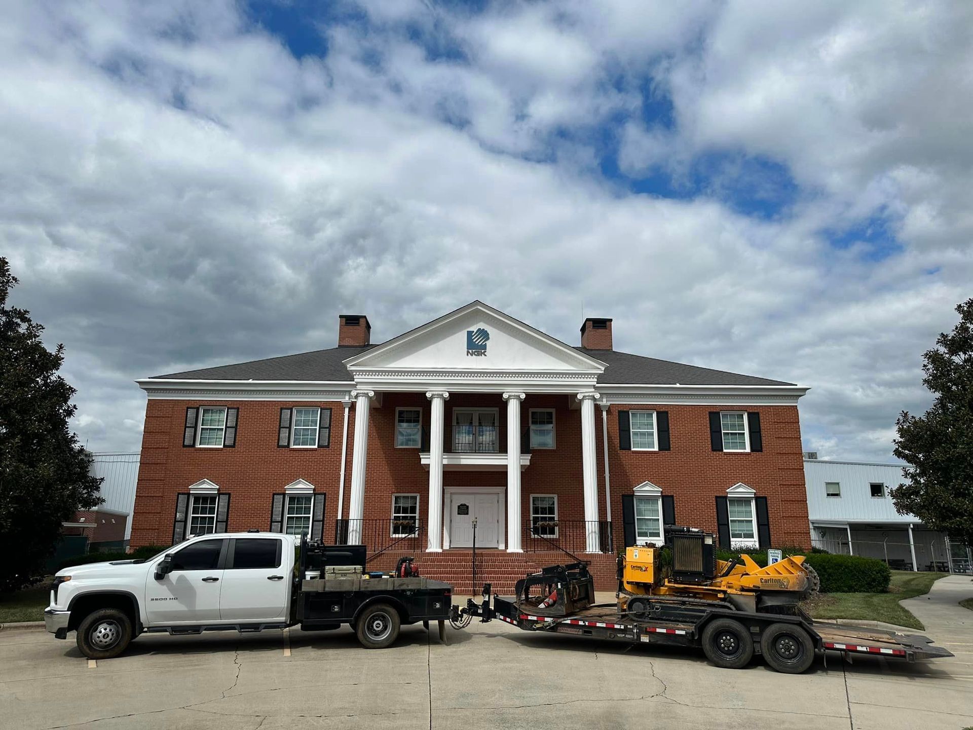 A white truck is parked in front of a large brick building.
