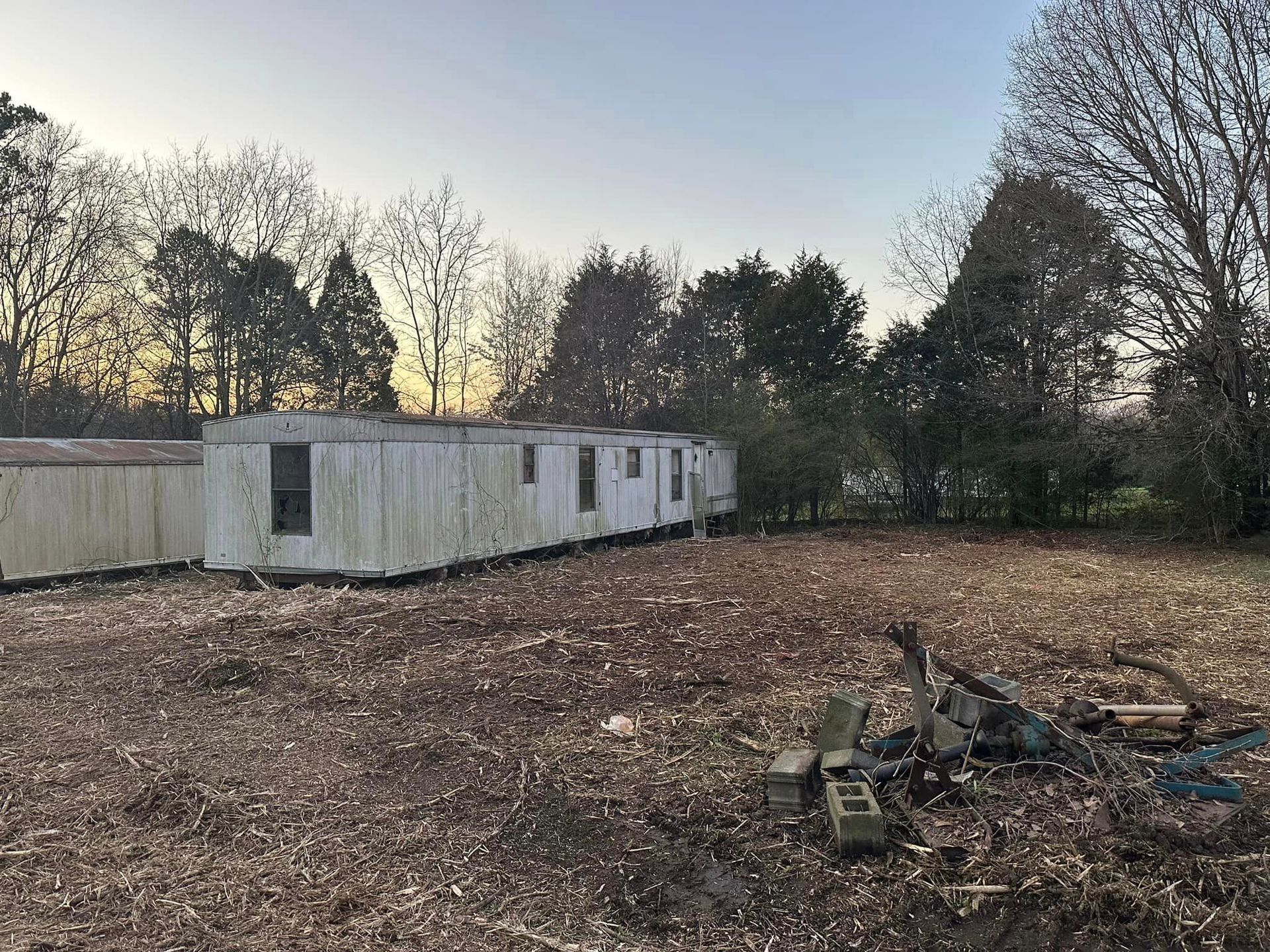 A row of mobile homes are sitting in a field with trees in the background.