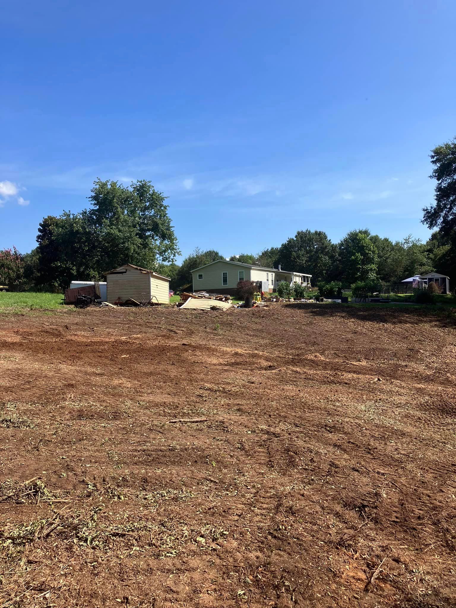 A large dirt field with a house in the background.