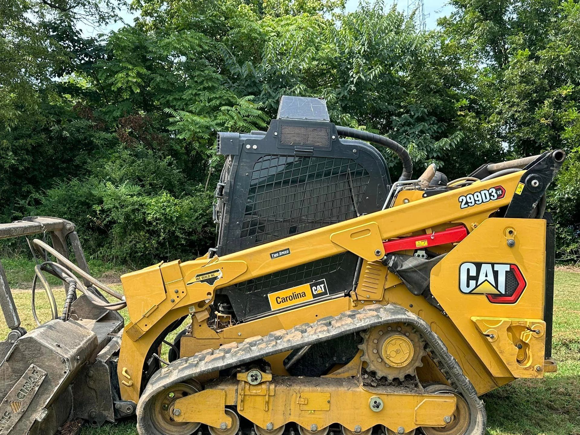 A yellow and black cat tractor is parked in a grassy field.
