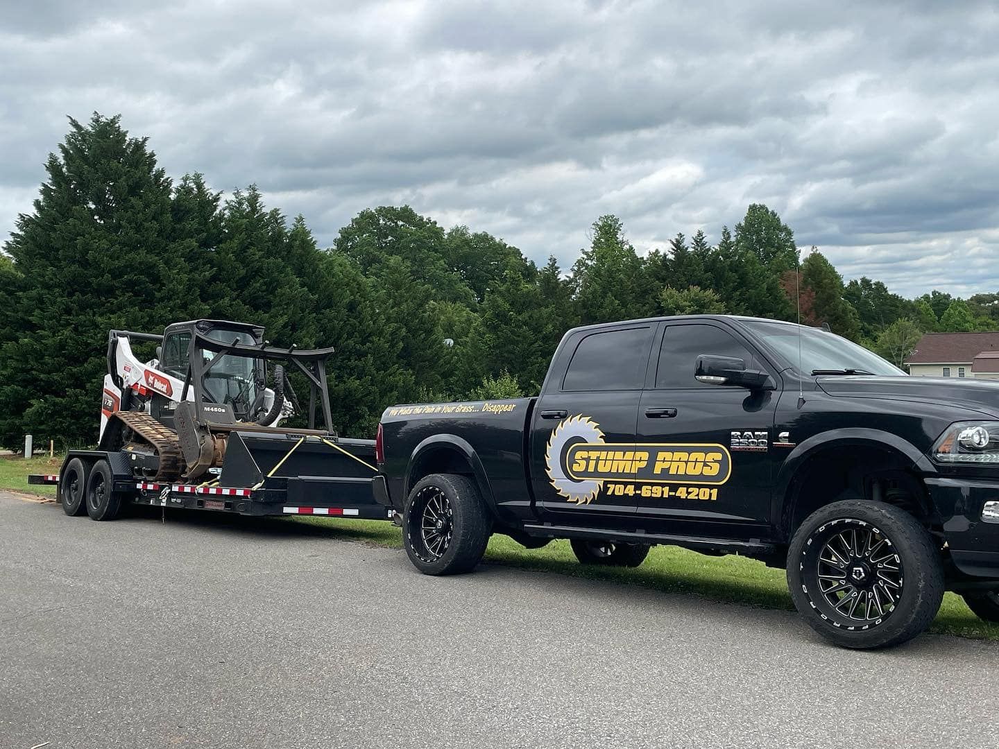 A black truck is towing a bulldozer on a trailer.