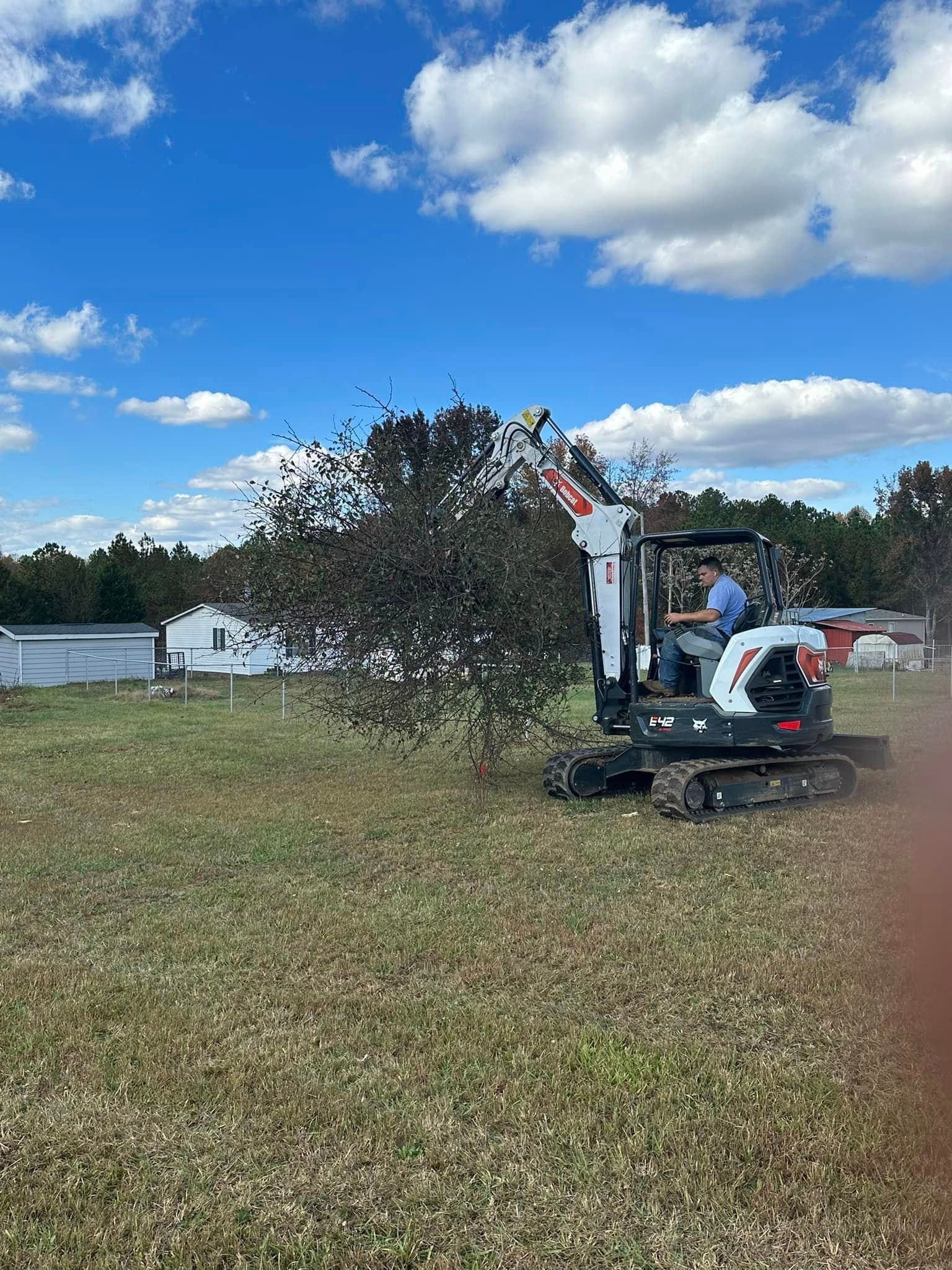 A man is driving a small excavator in a field.