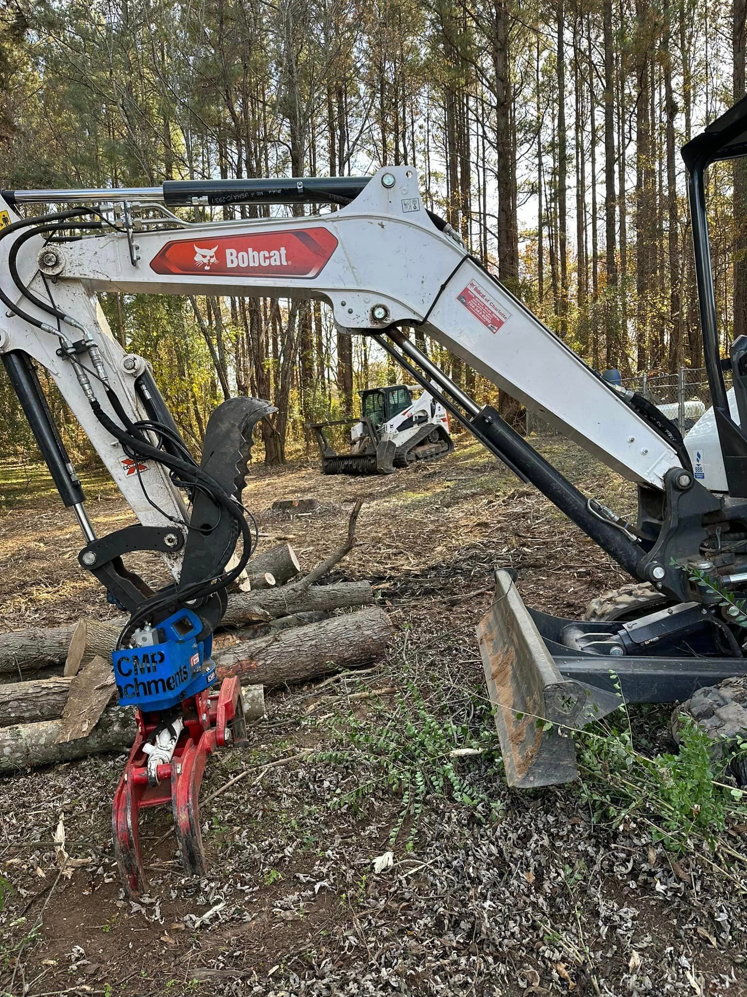 A bobcat excavator is sitting in the middle of a forest.