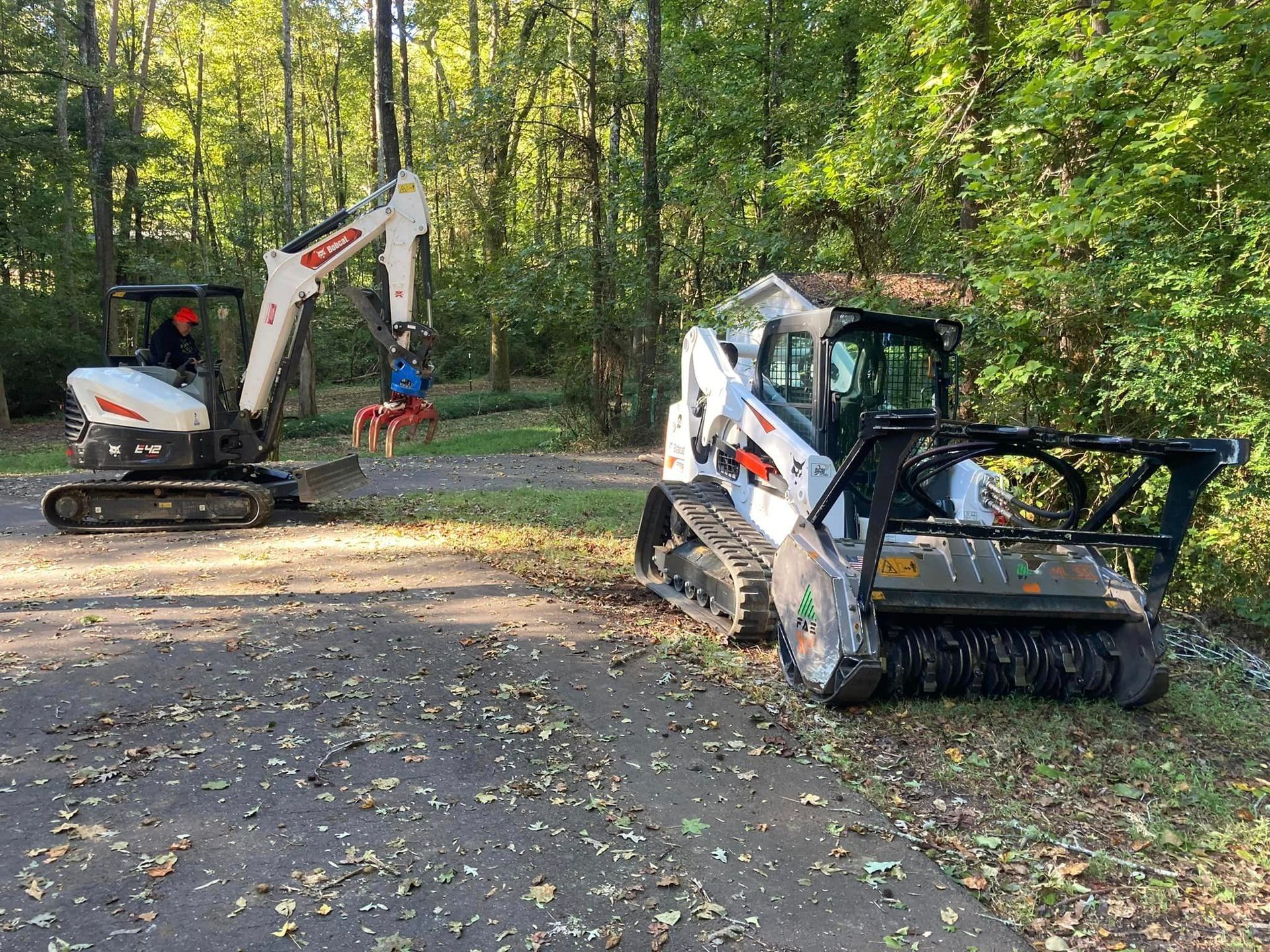A bulldozer and a brush mower are parked on the side of a road.