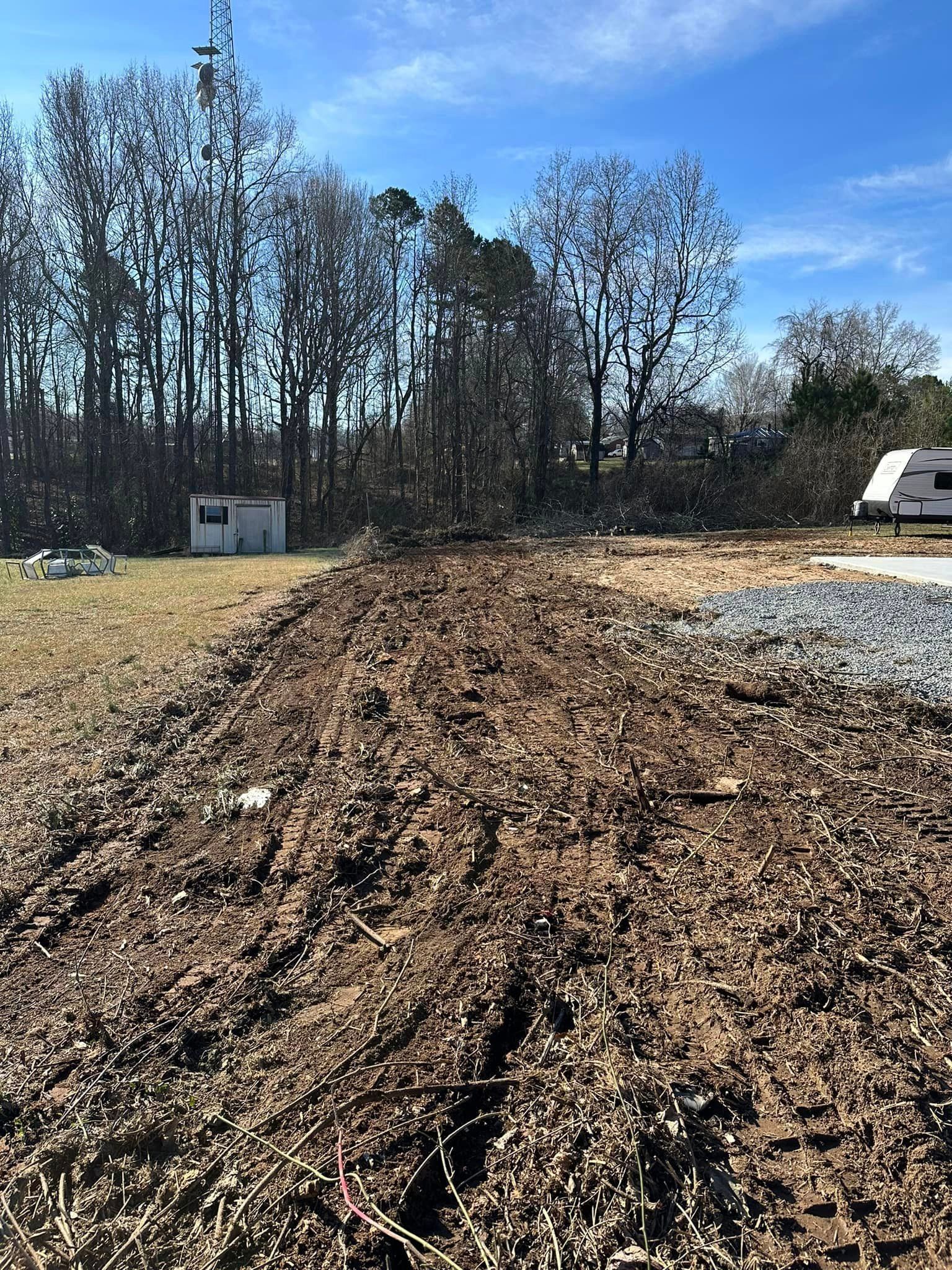 There is a lot of dirt in the middle of a field with trees in the background.
