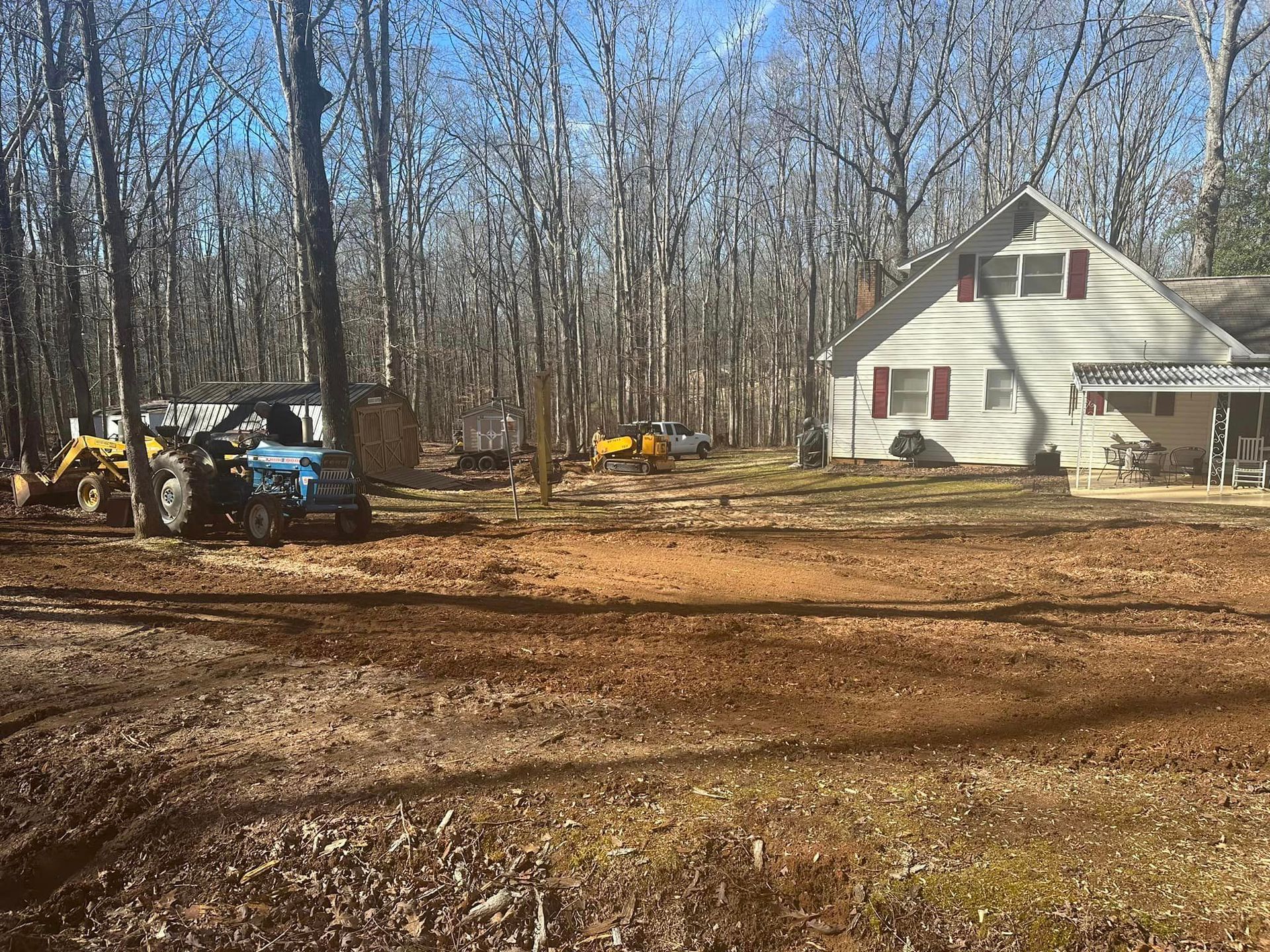 A tractor is parked in front of a house in the woods.