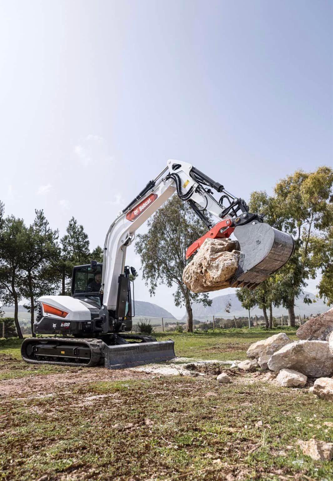 A bulldozer is lifting a large rock in a field.