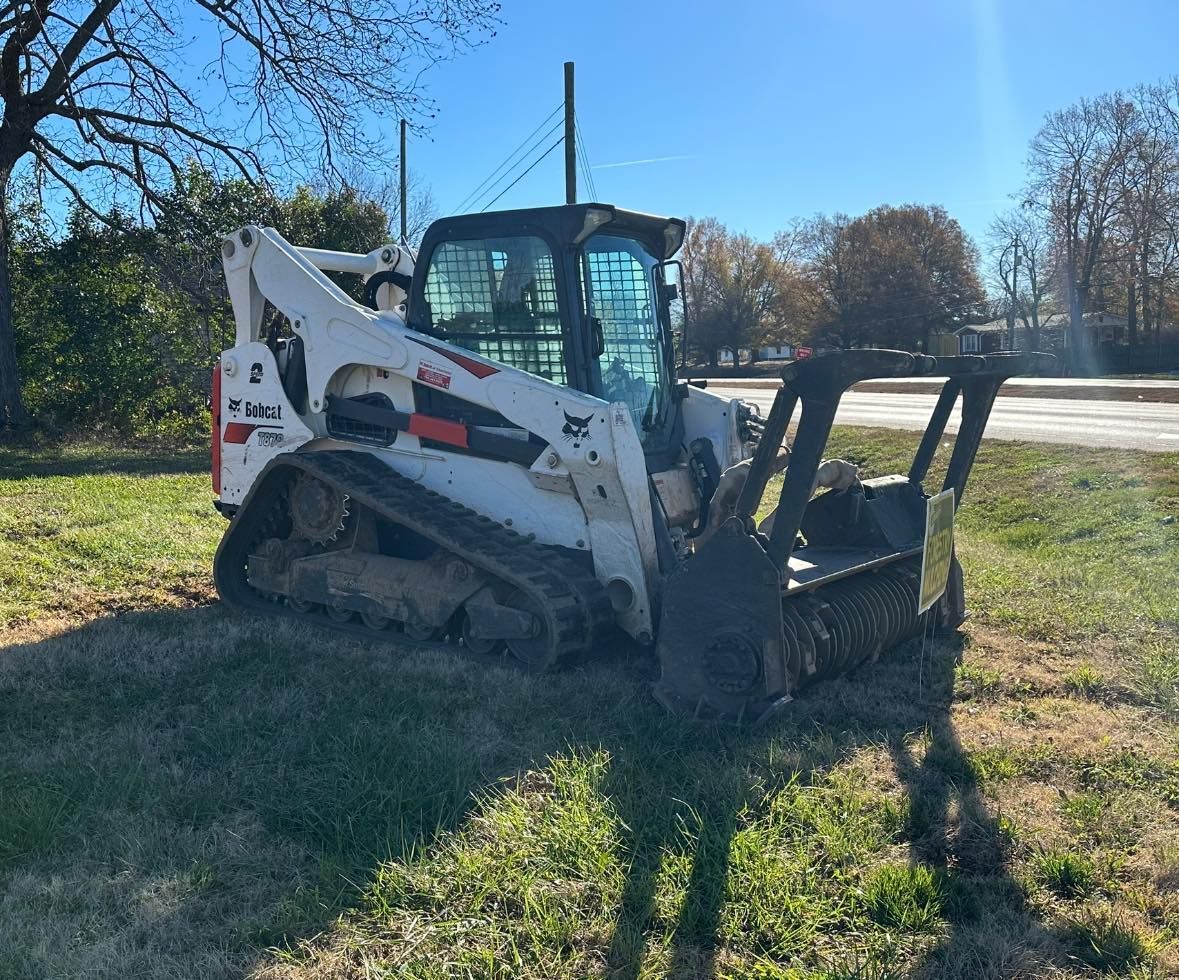 A bobcat tractor is parked in a grassy field