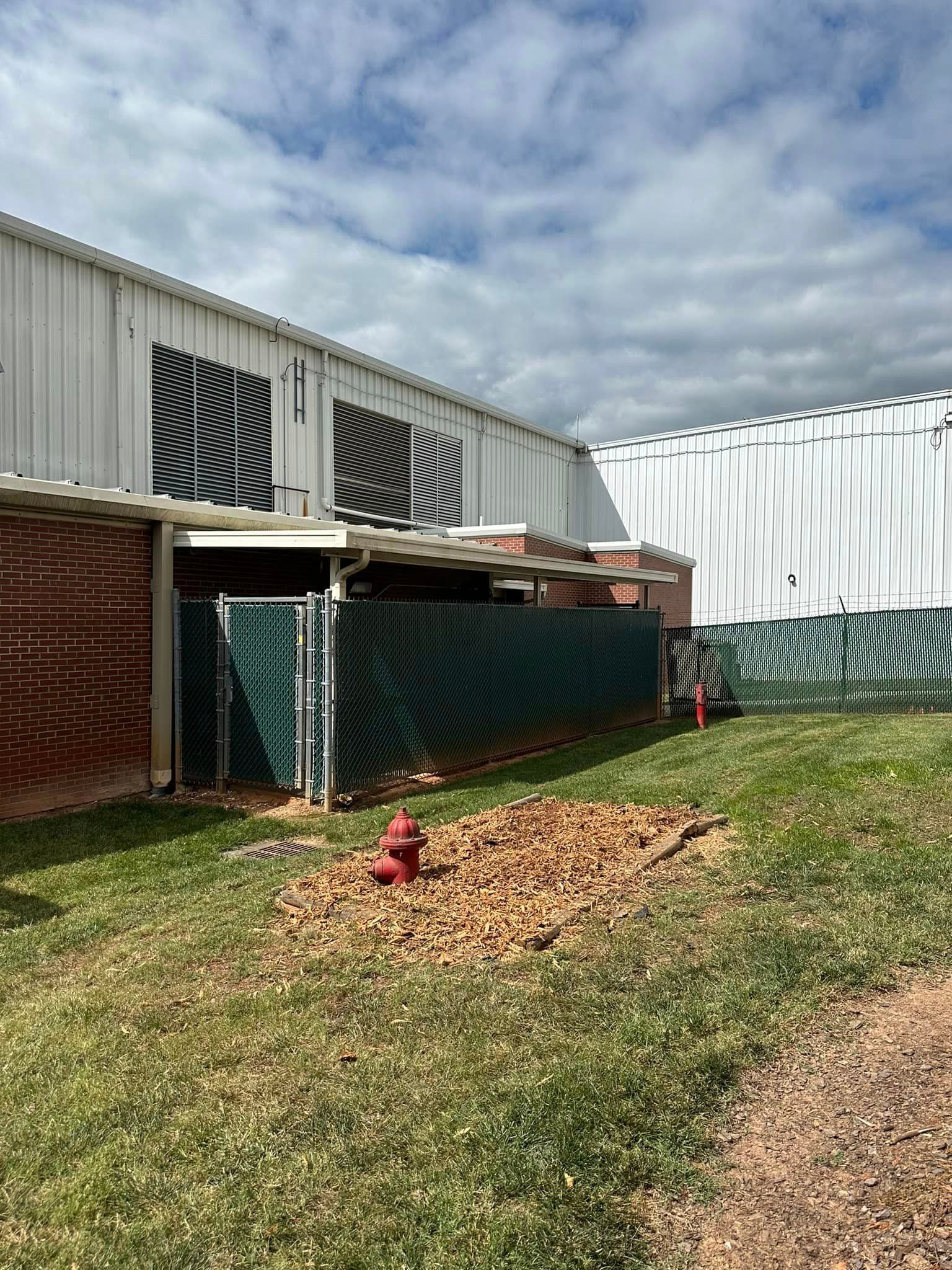 There is a fire hydrant in the grass in front of a building.