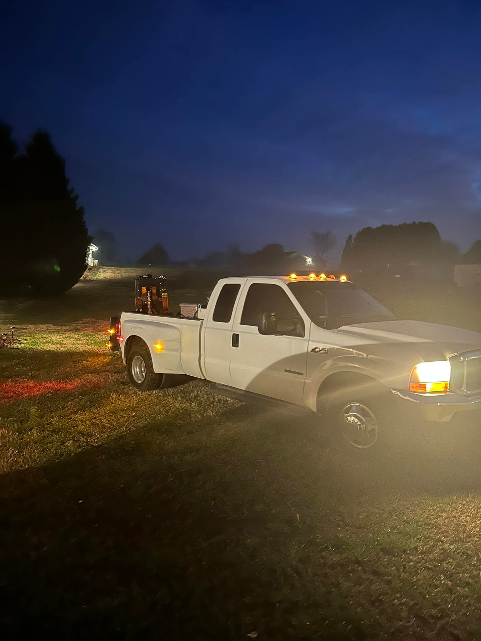 A white truck is parked in a field at night.